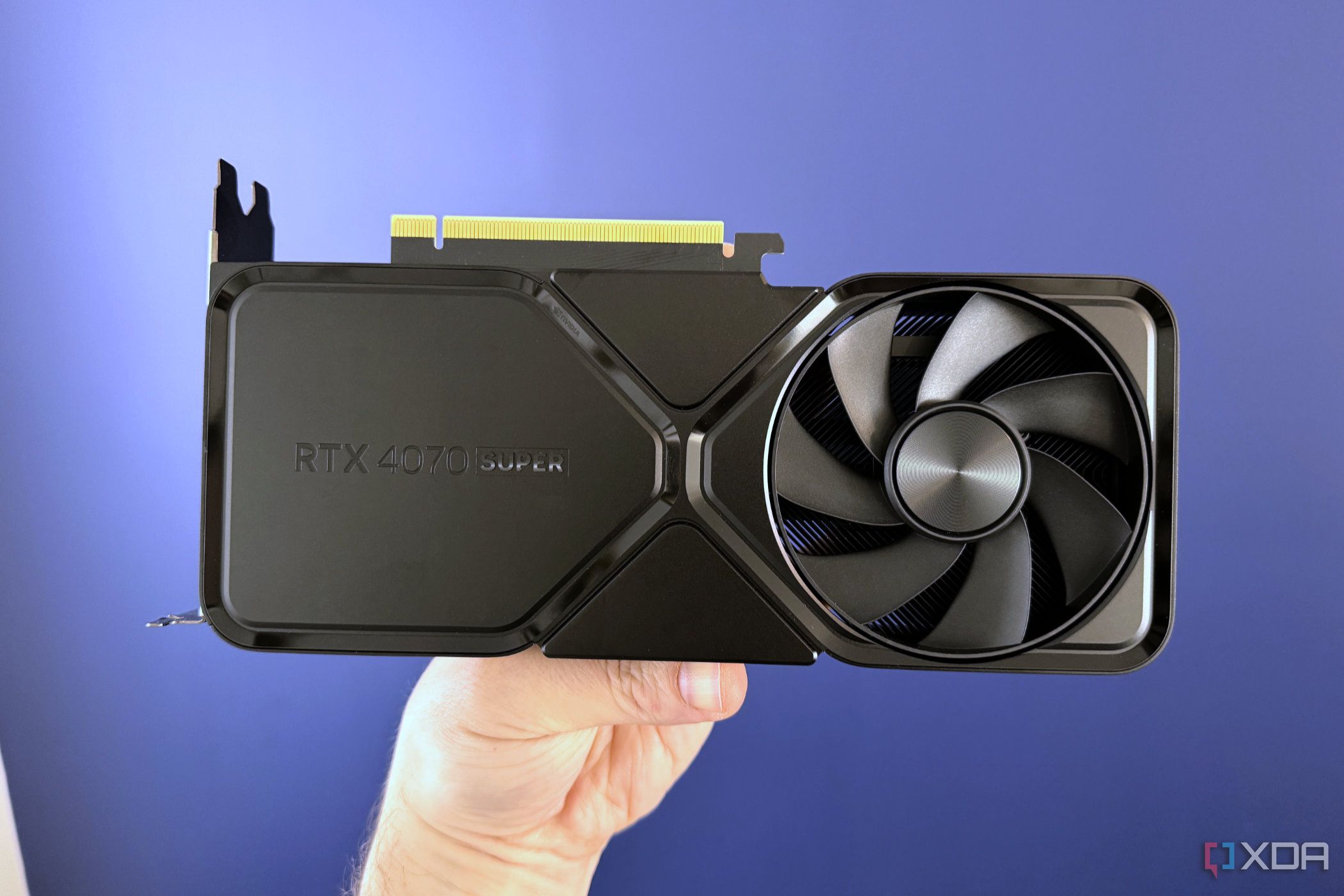 nvidia geforce rtx 4070 super founders edition held in front of blue wall