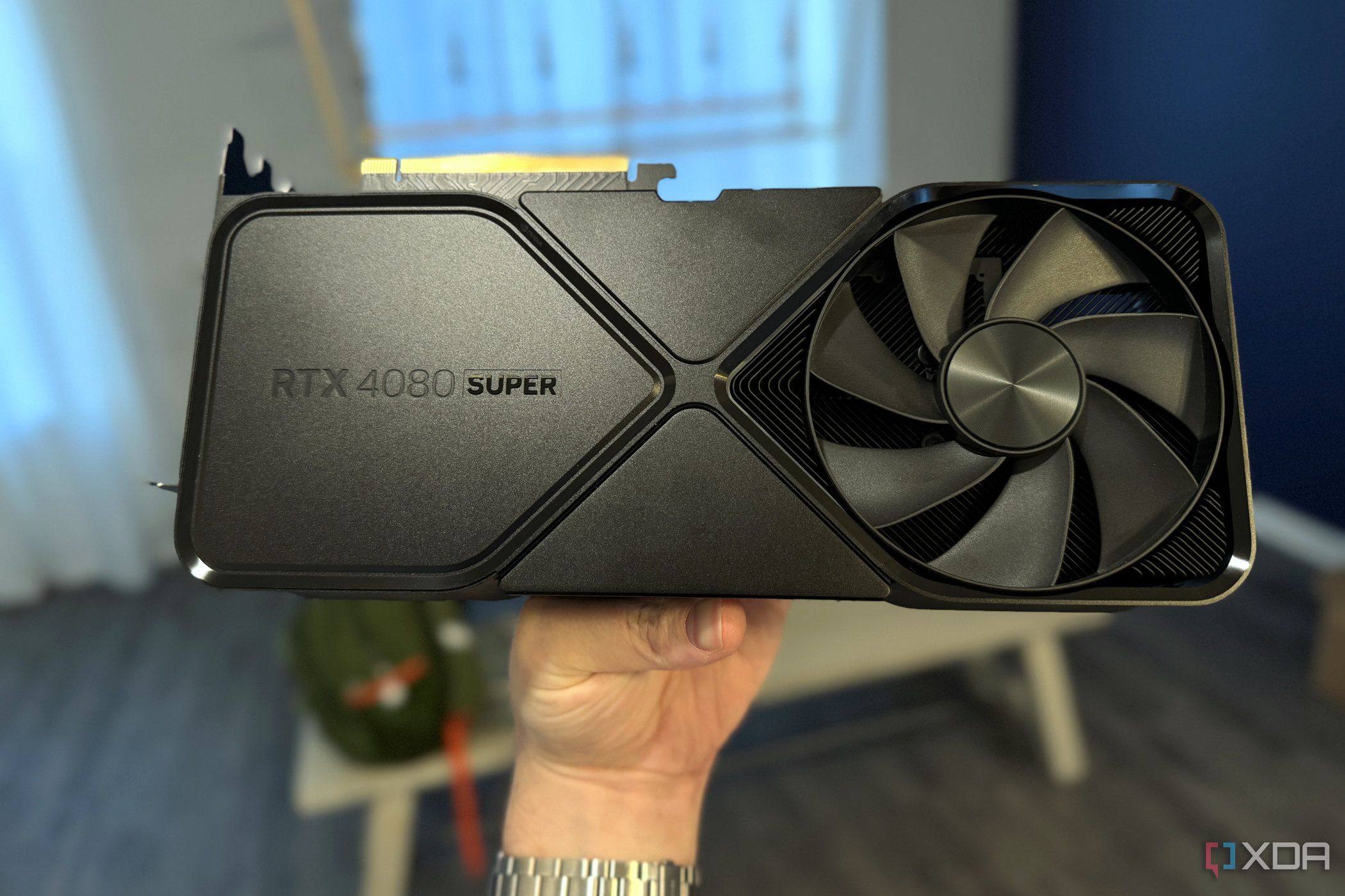 nvidia geforce rtx 4080 super fe held in hand in a dining room