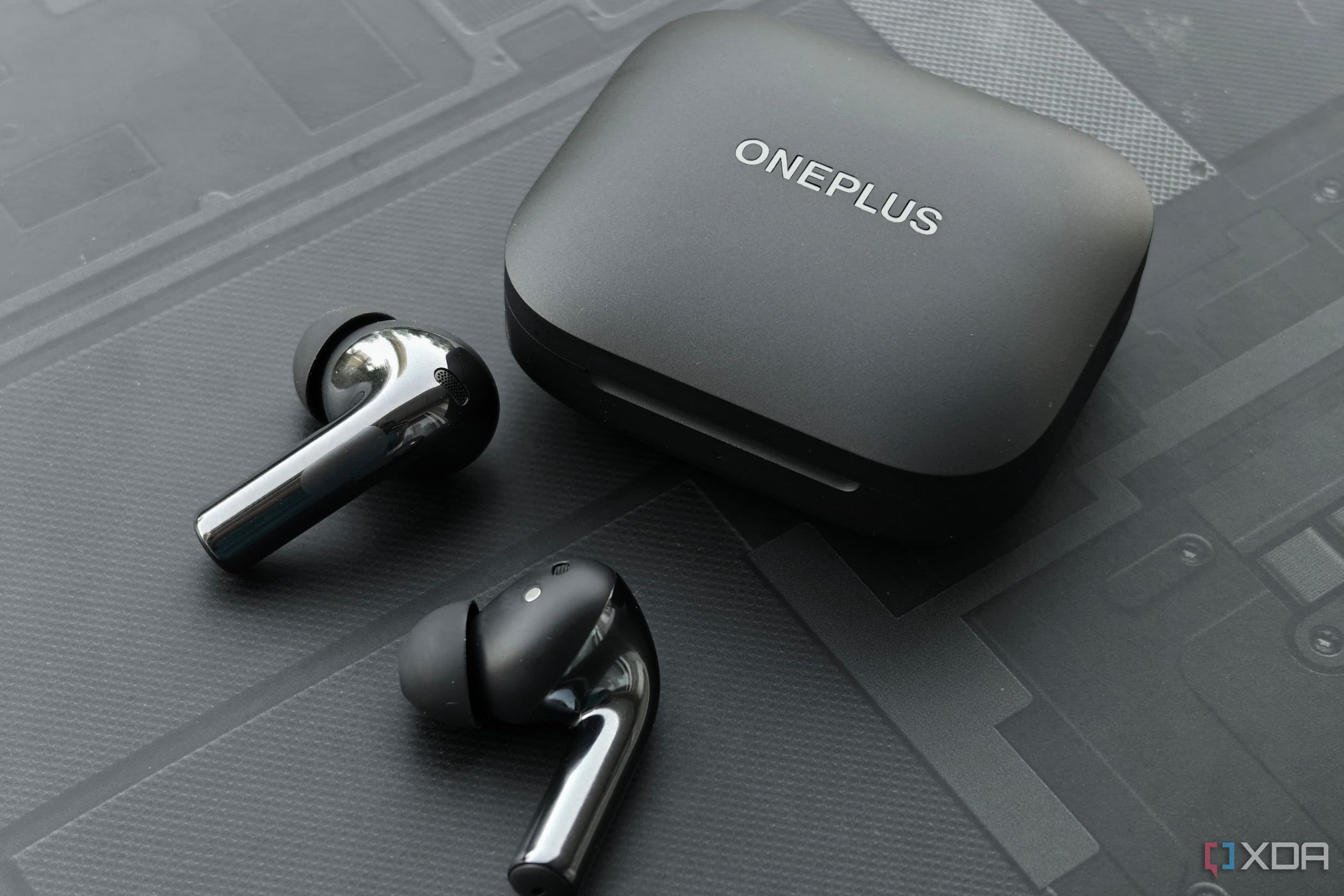 An image showing a pair of OnePlus Buds 3 earbuds sitting next to its charging case.