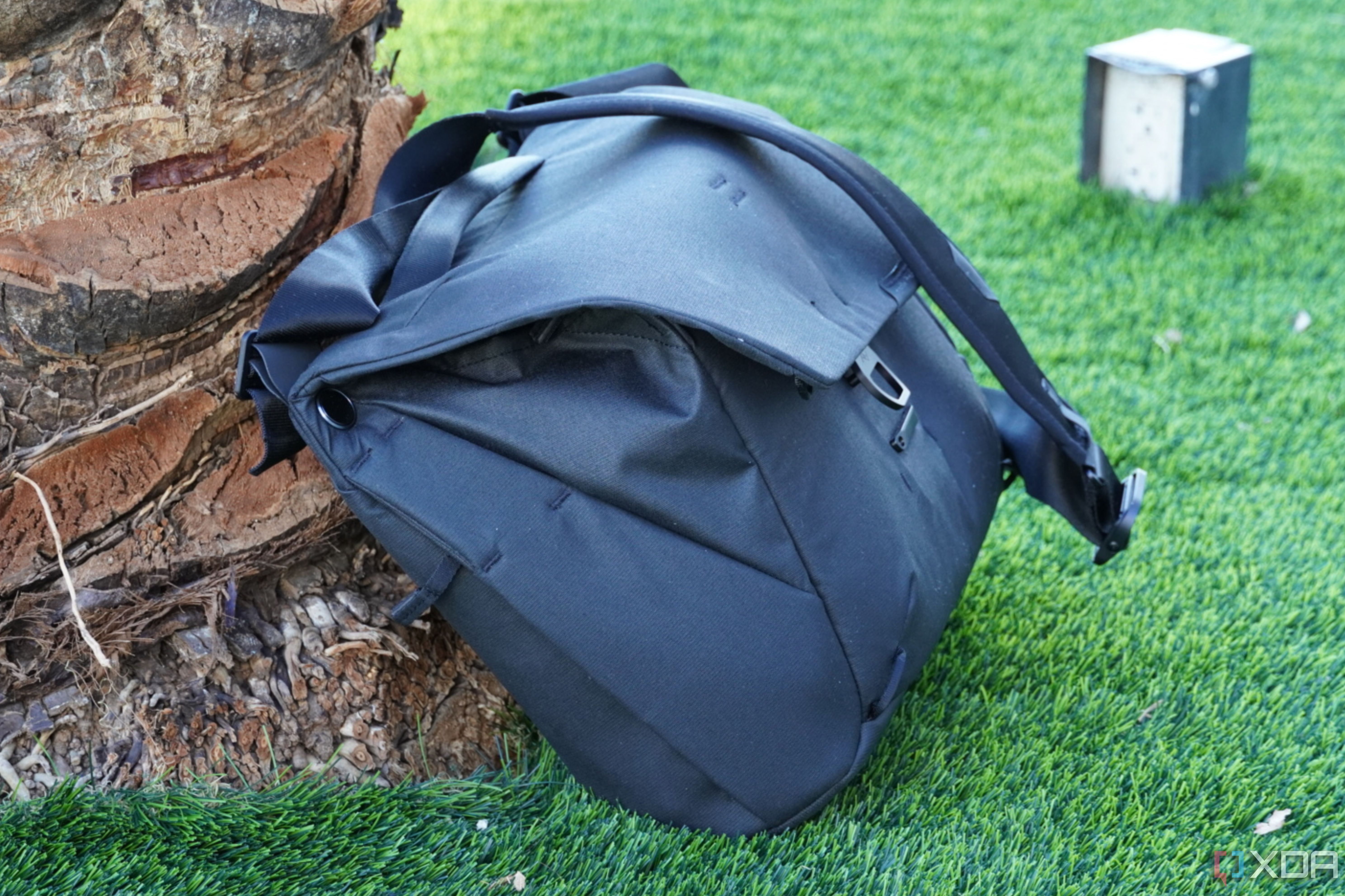The Peak Design Everyday Messenger leaning against a palm tree.