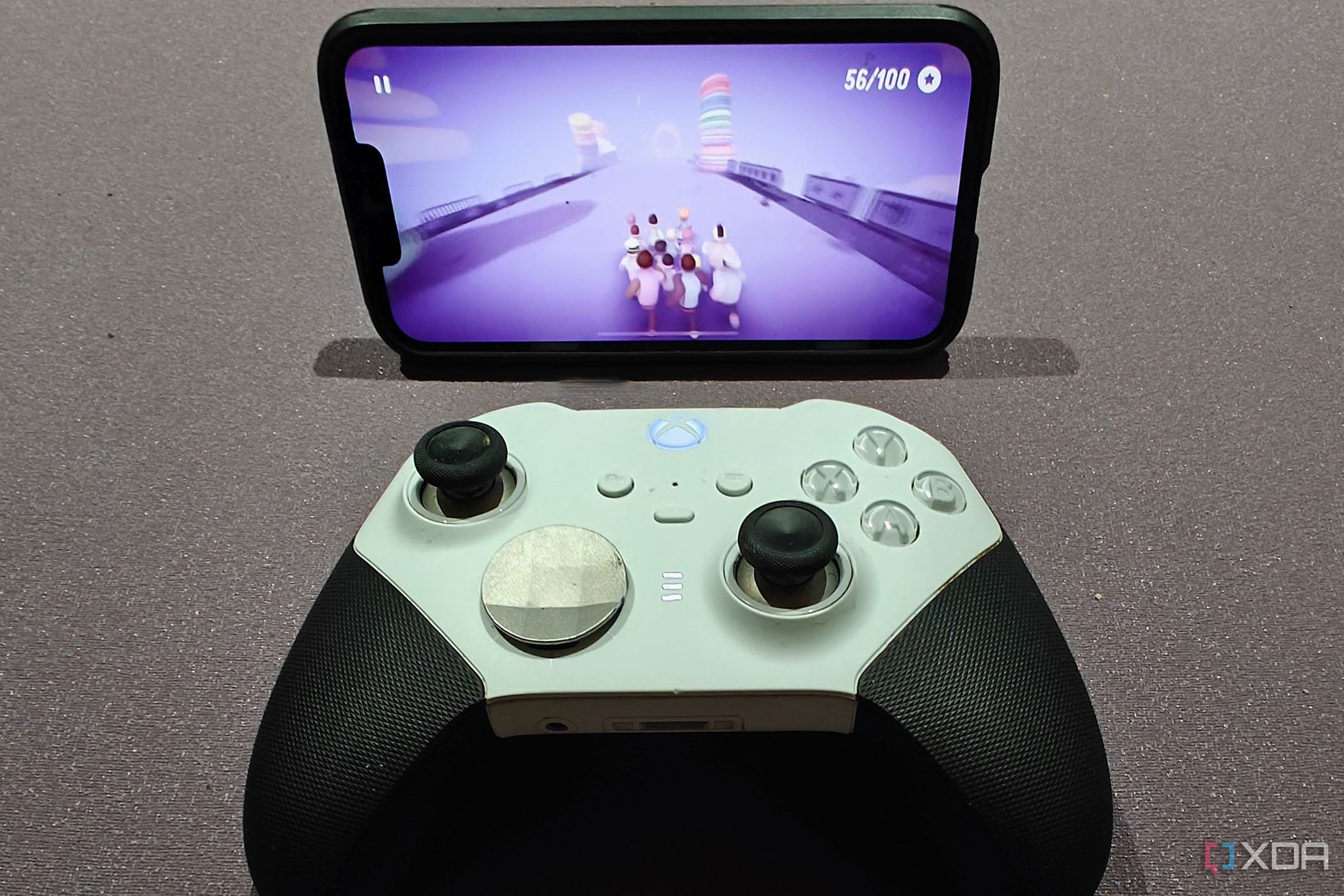 An Xbox controller in front of an iPhone showing the game Populus Run.