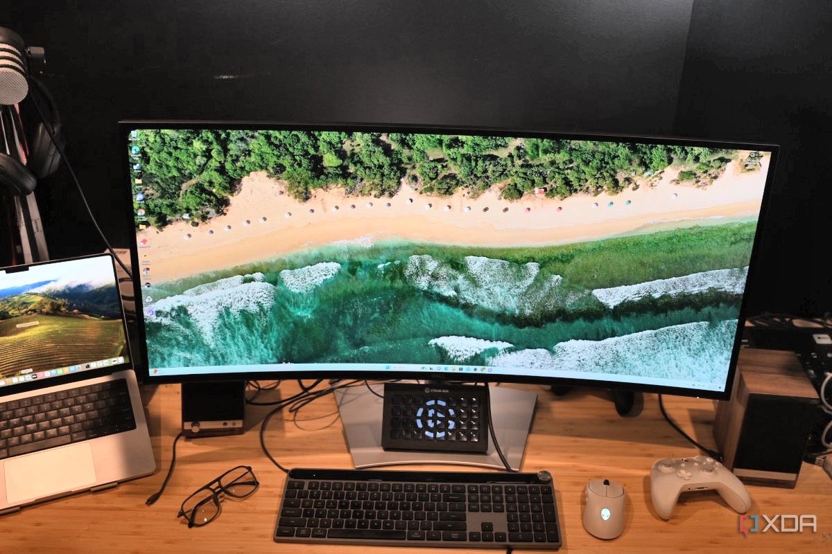 Front shot of Dell UltraSharp 40 Curved Thunderbolt Hub Monitor with MacBook Pro, glasses, Legato Stream Deck, white wireless mouse and white Xbox controller