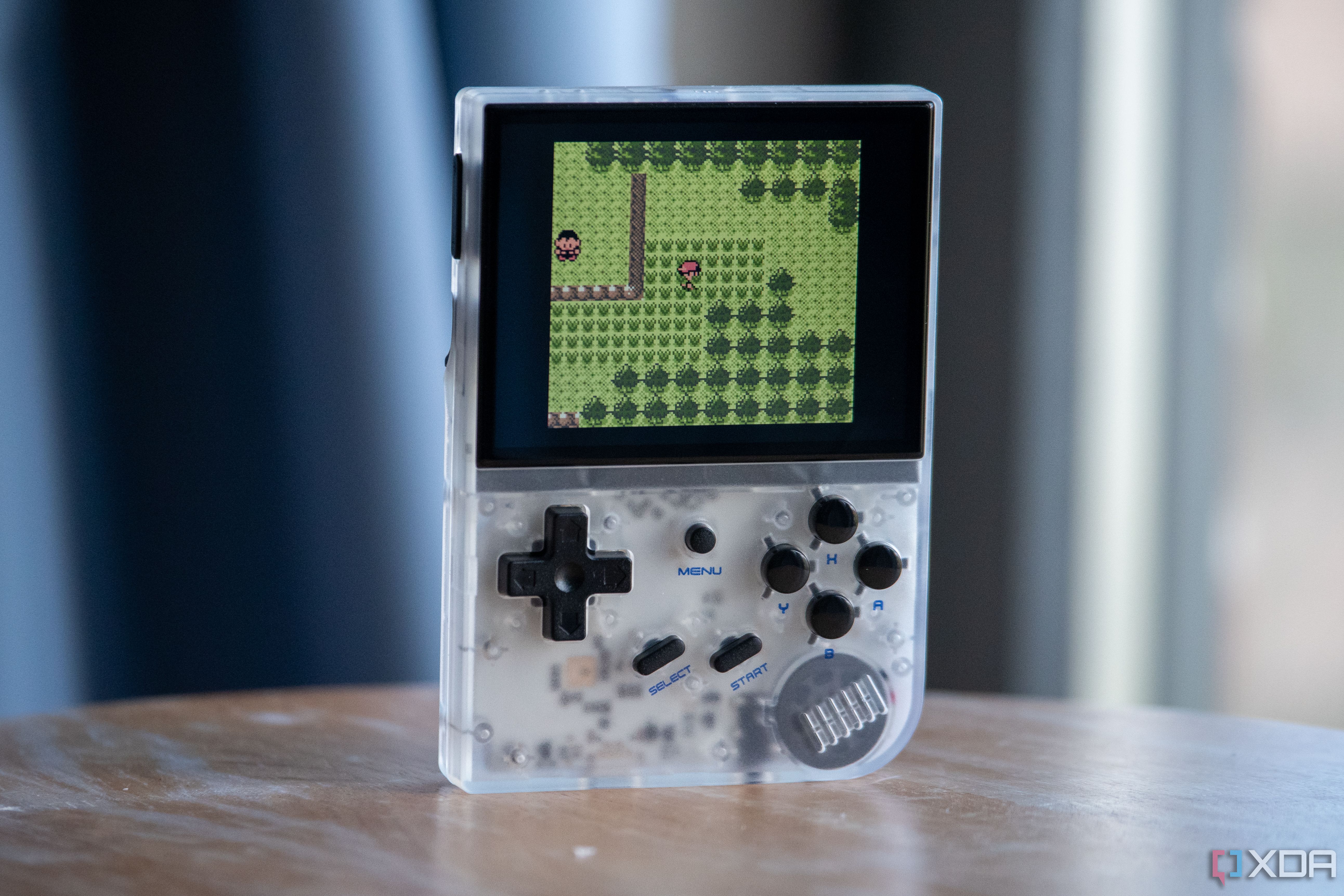 Anbernic RG35XX on a table, showing front buttons and Pokemon running on it