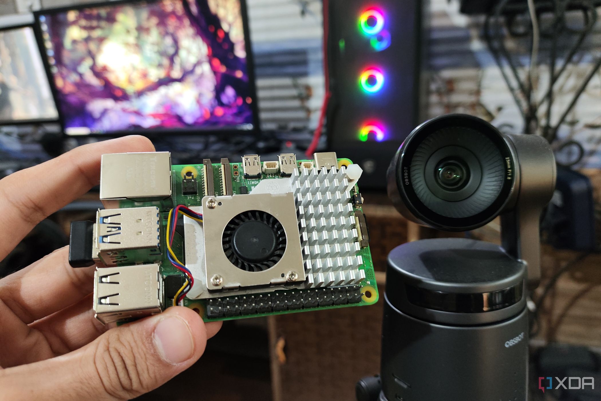 A Raspberry Pi 5 kept near an Obsbot Tail Air webcam, with a PC in the background