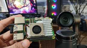A Raspberry Pi 5 kept near an Obsbot Tail Air webcam, with a PC in the background