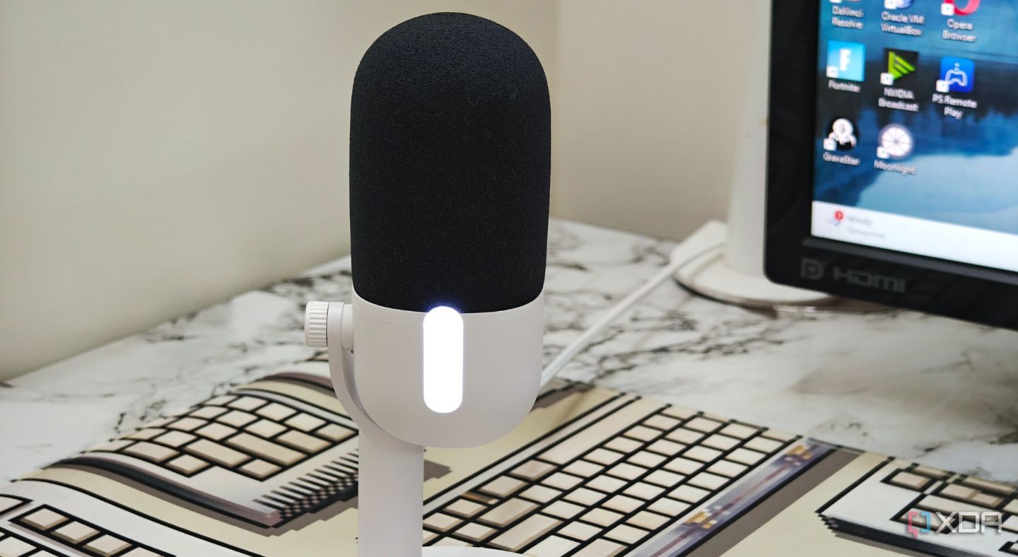 An image showing the Elgato Wave Neo microphone kept on a deskmat next to a monitor.