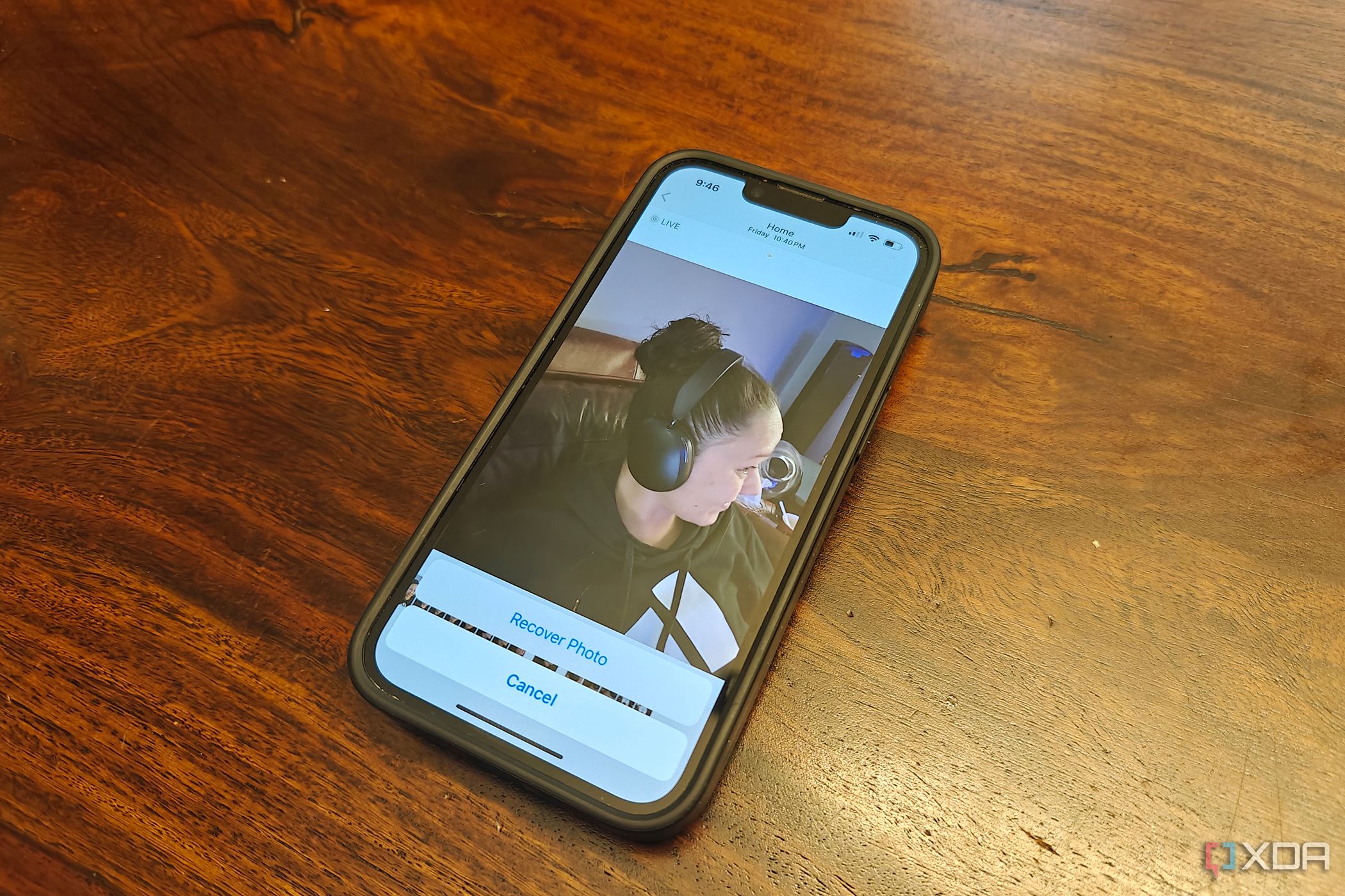 Un iPhone sobre una mesa que muestra una foto de una mujer con auriculares y Recuperar foto en la parte inferior.