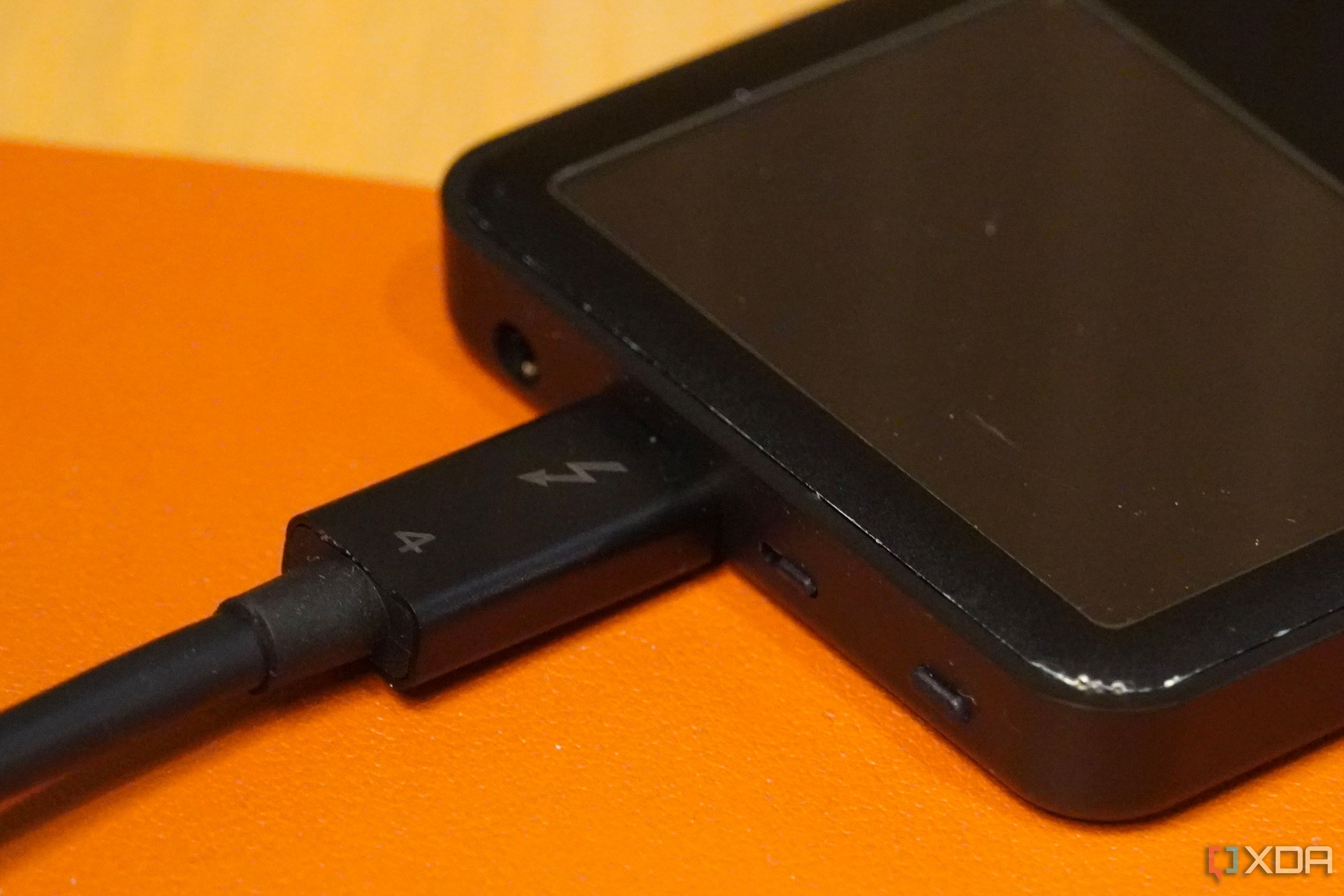 Un primer plano de un cable Thunderbolt 4 conectado a un iPod Classic.