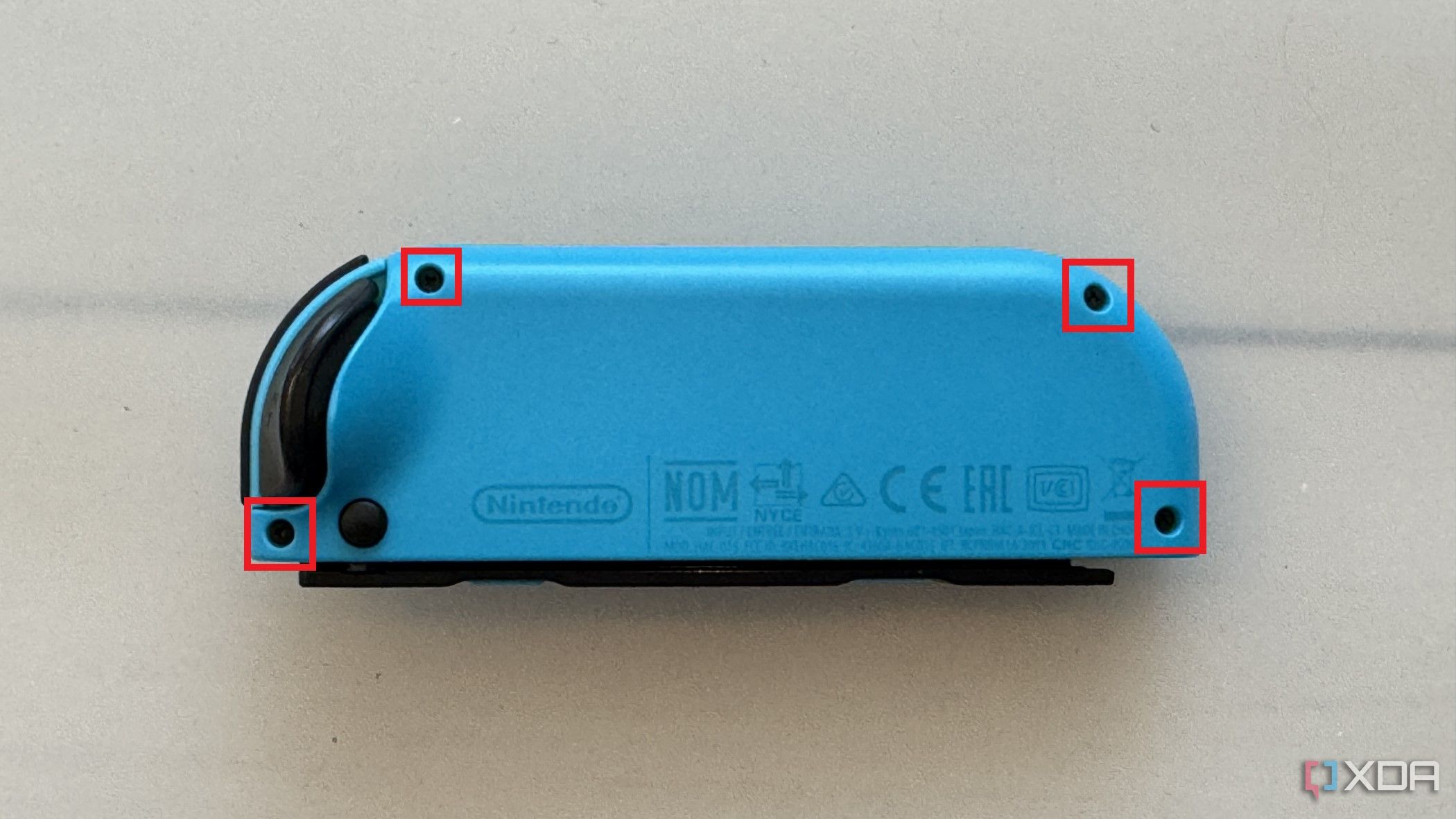 Joy-con izquierdo de Nintendo Switch visto desde atrás con cuatro orificios para tornillos marcados