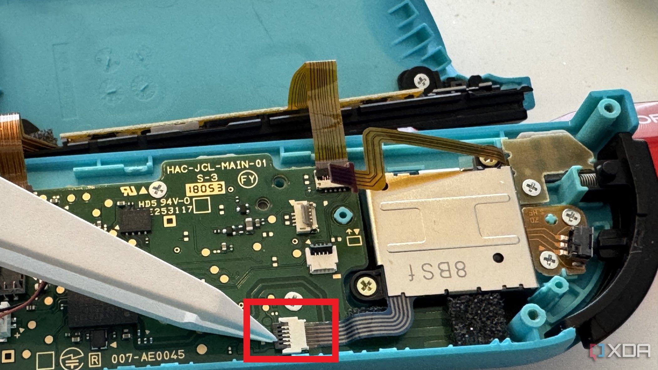 Interior del Joy-Con izquierdo de un Nintendo Switch que muestra la extracción del cable del joystick