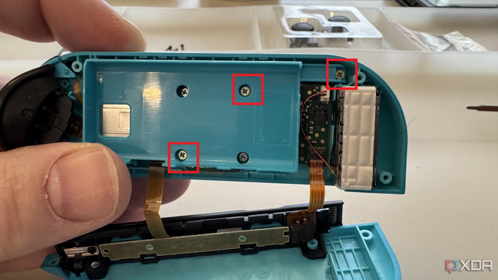 Interior de un Joy-Con izquierdo de Nintendo Switch que muestra los tres tornillos para quitar la placa intermedia