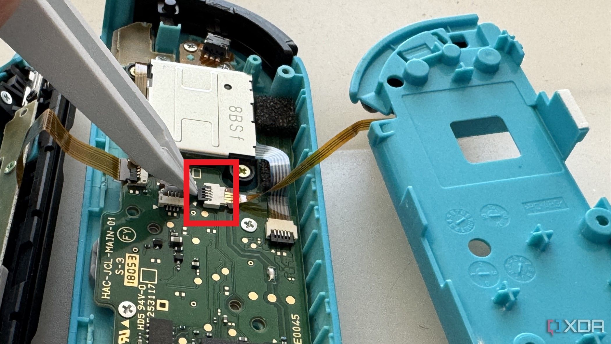 Interior del Joy-Con izquierdo de un Nintendo Switch que muestra la extracción del cable del botón ZL