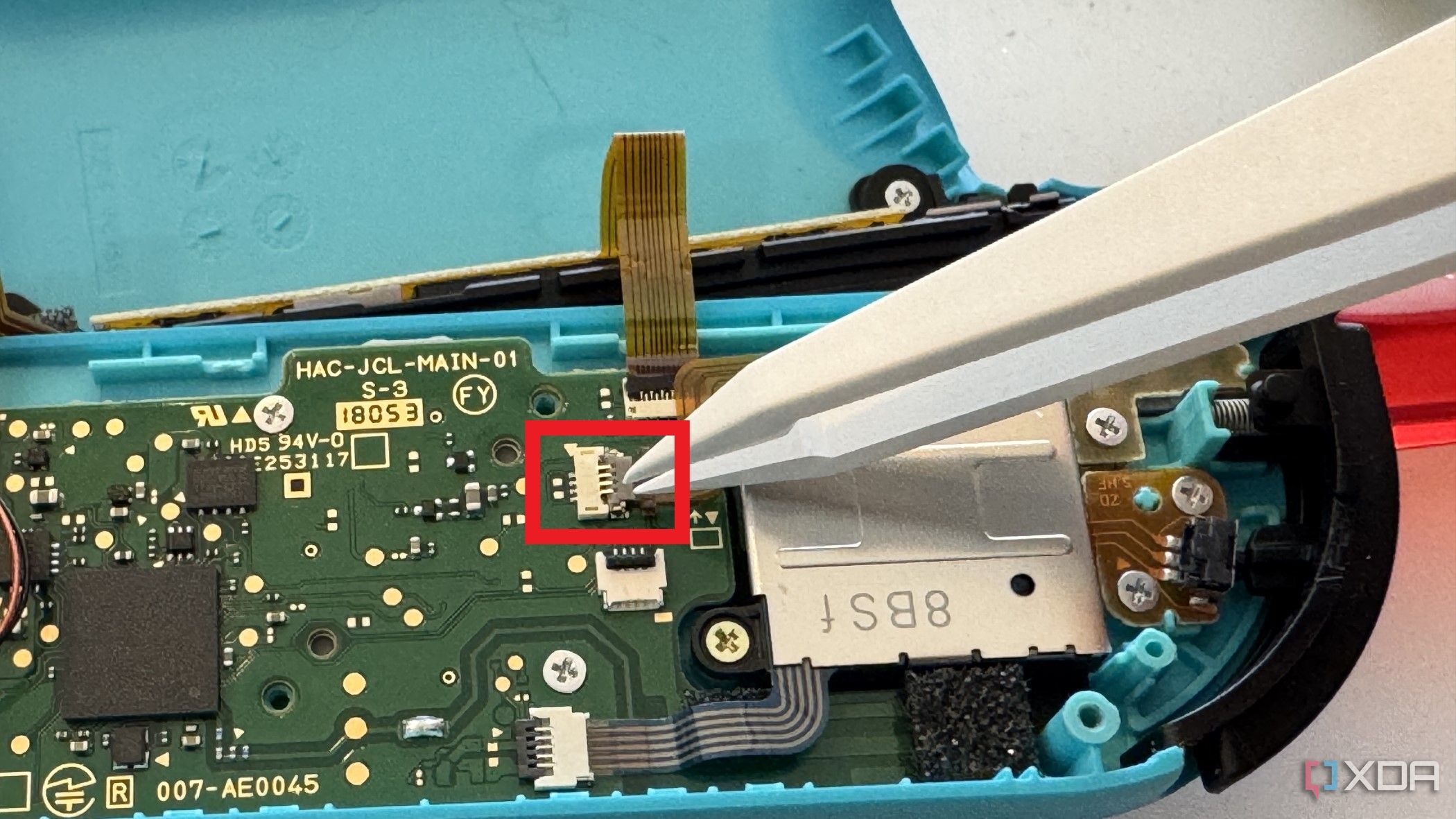 Interior del Joy-Con izquierdo de un Nintendo Switch que muestra la extracción del cable del botón menos