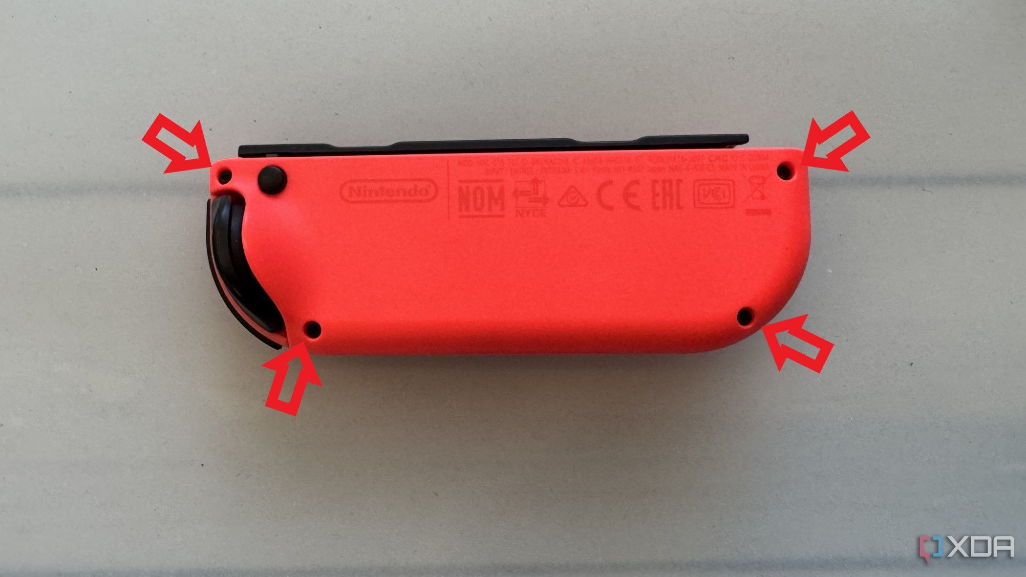 Joy-Con derecho de Nintendo con las posiciones de los tornillos en la placa posterior resaltadas