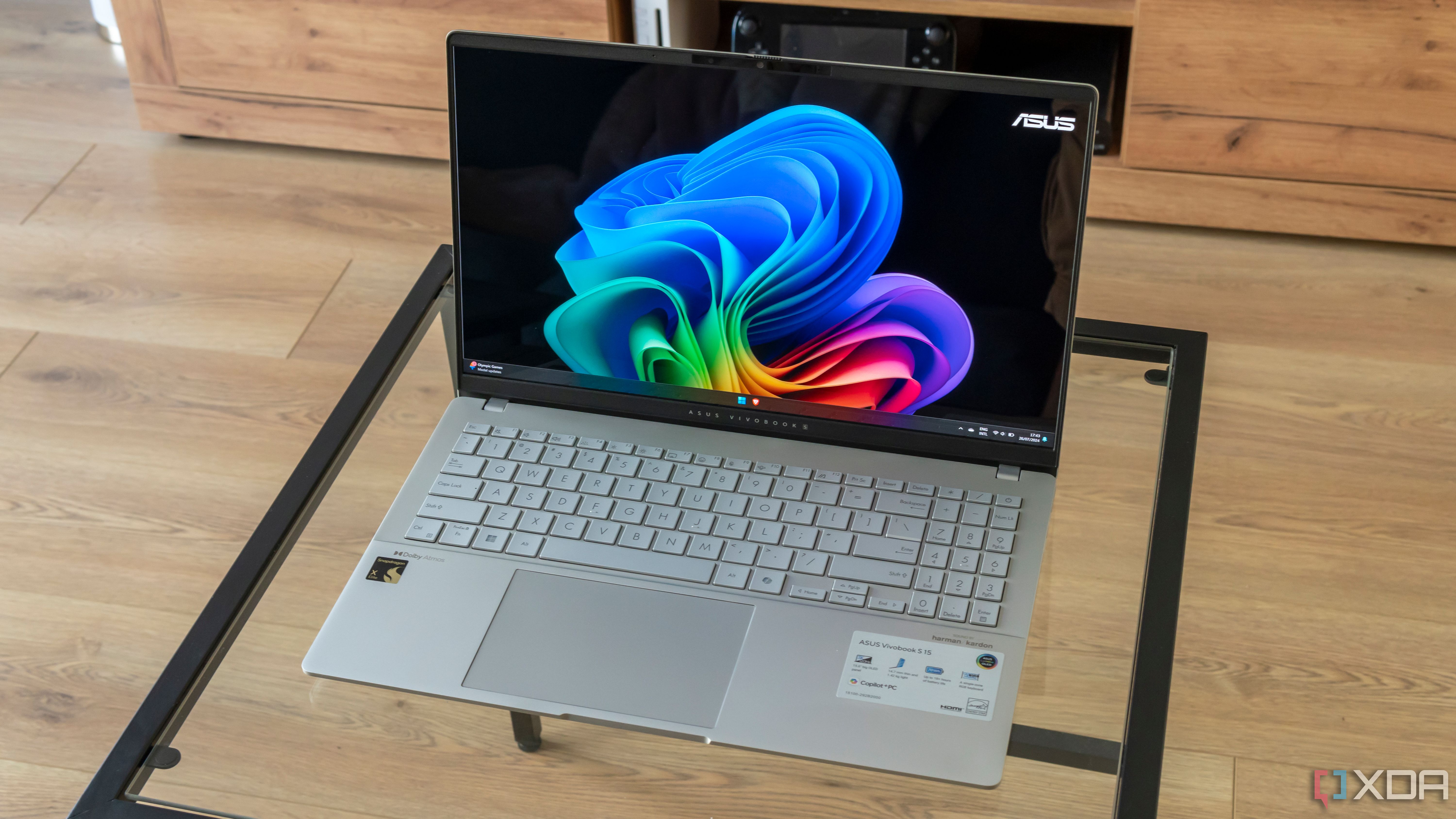 Angled view of the Asus Vivobook S 15 showinf the Windows 11 desktop on a glass table