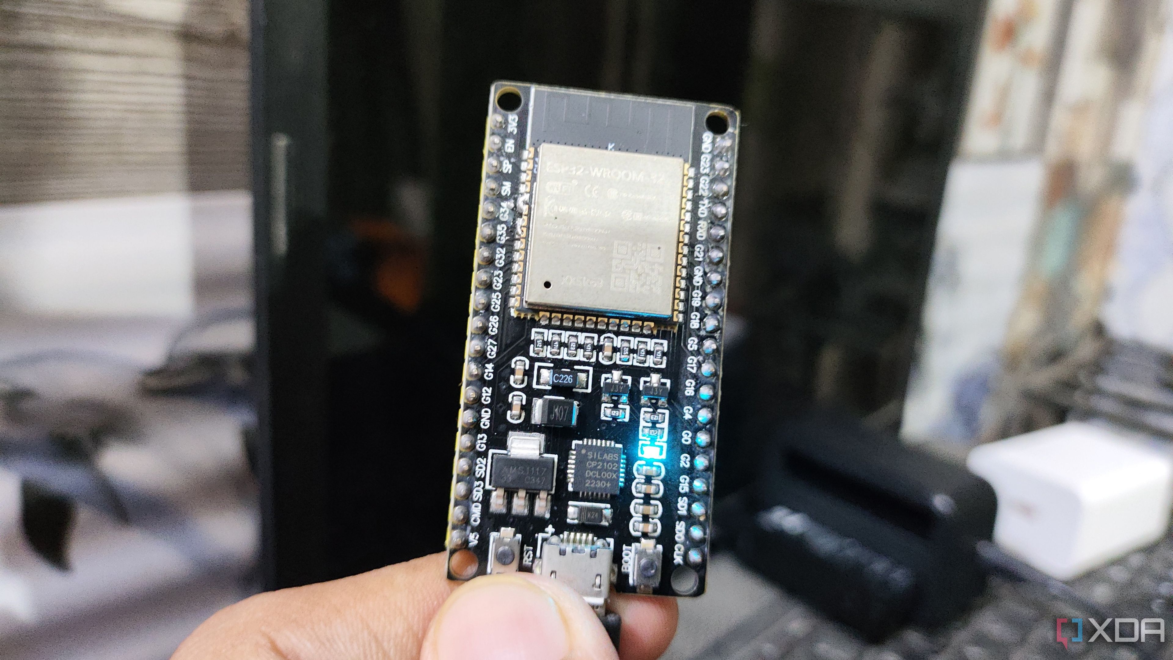 Una persona sosteniendo un ESP32, con un LED encendido en el microcontrolador.