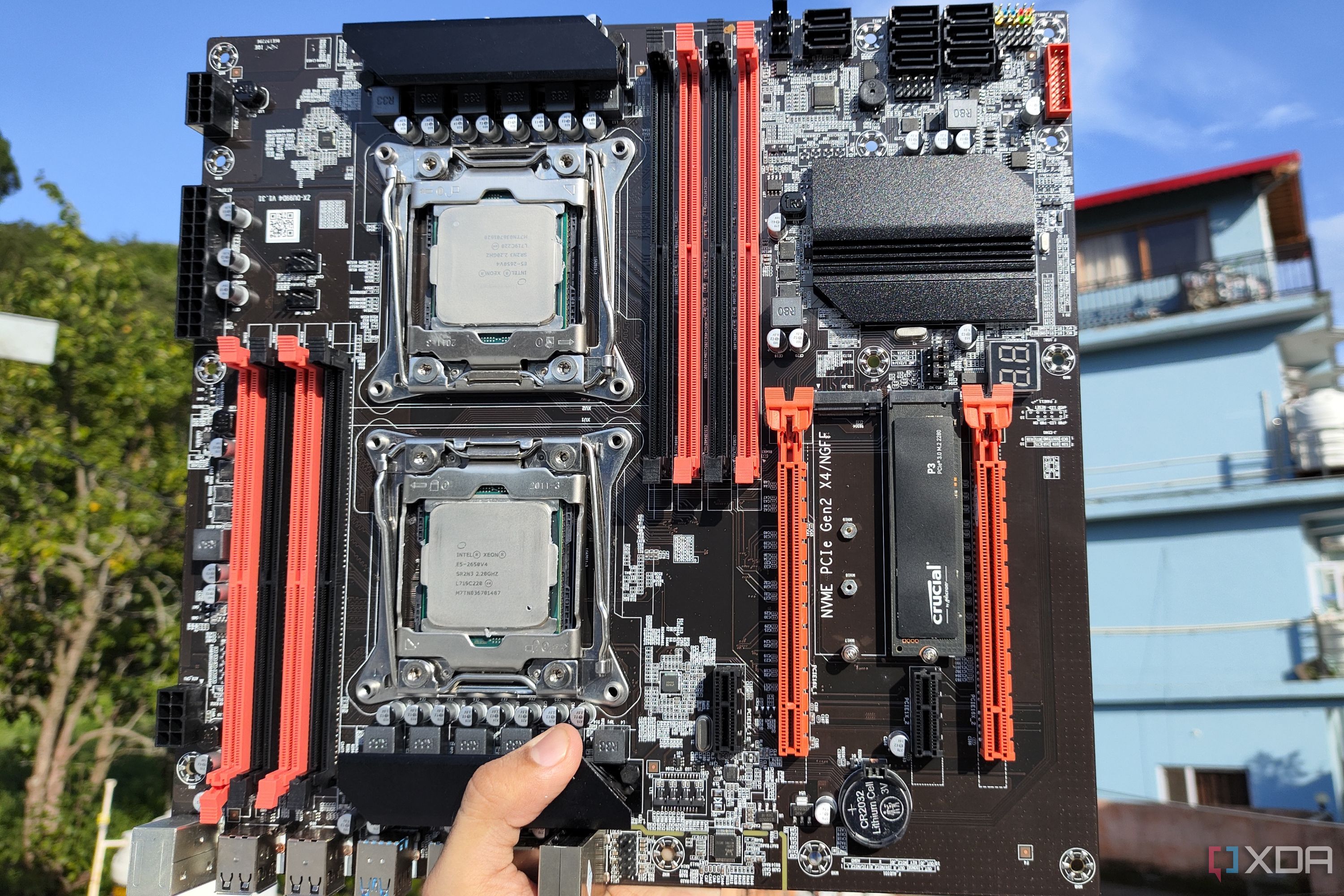 A person holds an X99 server motherboard with two Intel Xeon CPUs.