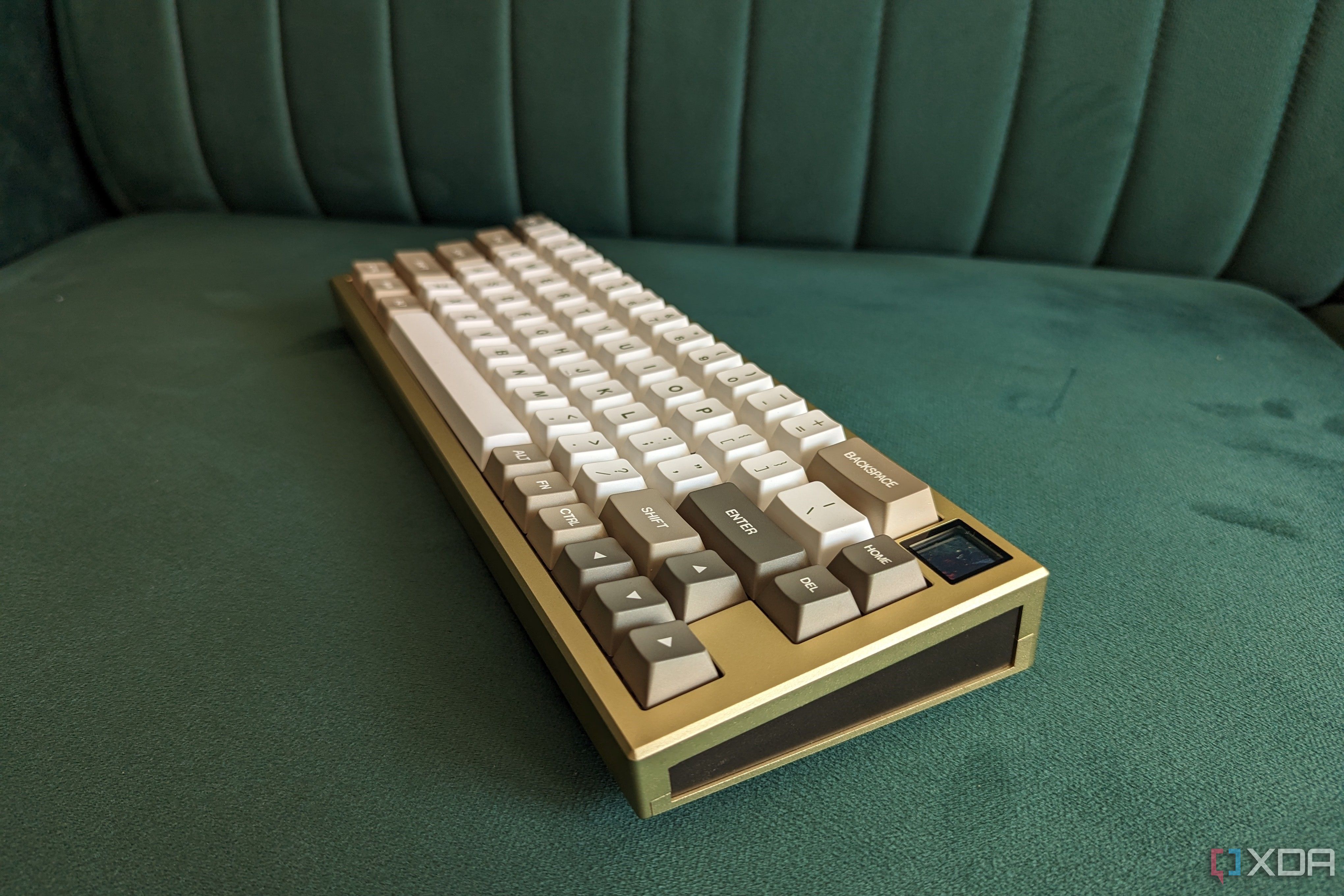 Un teclado mecánico dorado y blanco sobre una superficie verde.