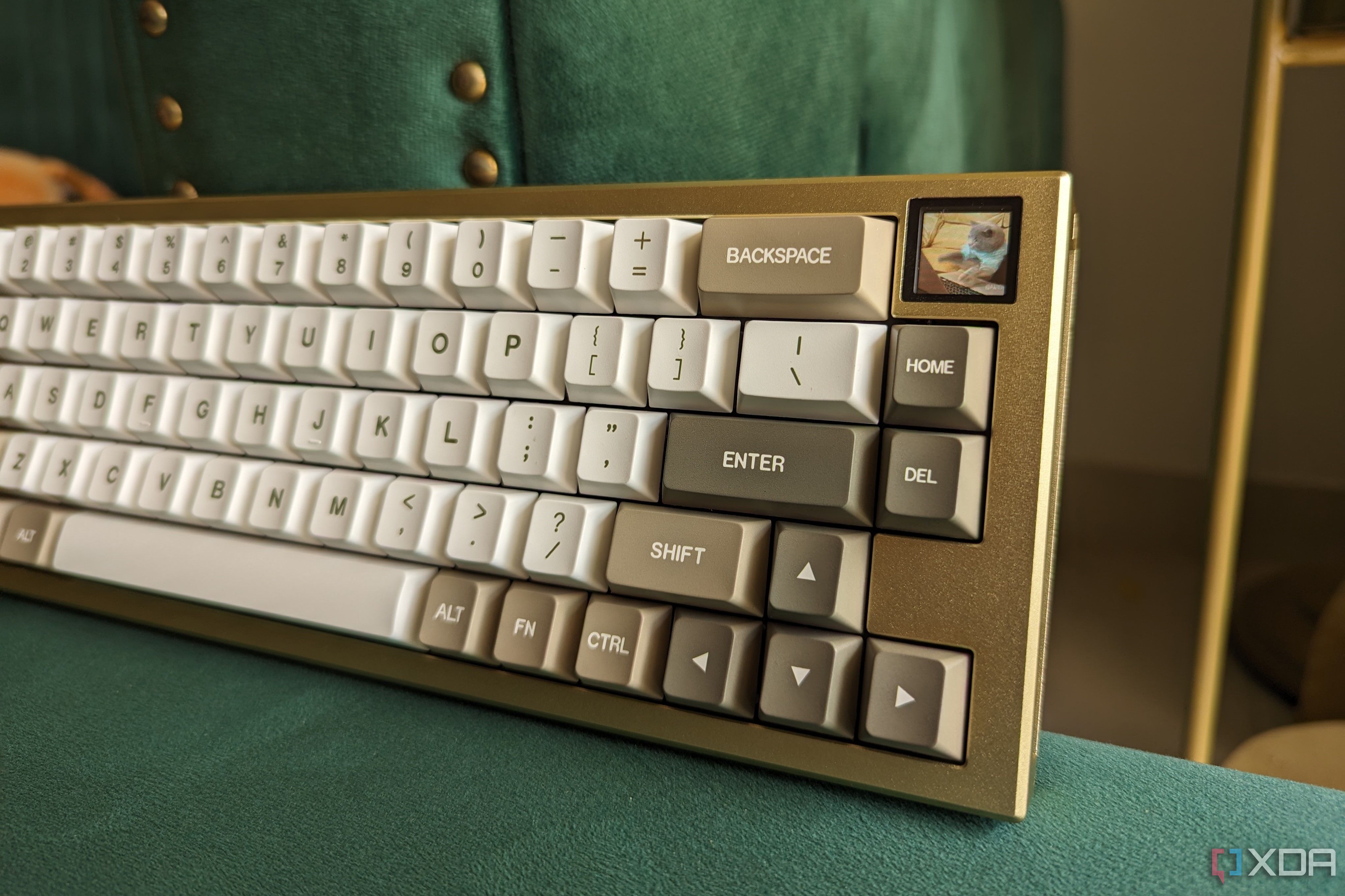 Un teclado mecánico dorado y blanco que muestra un GIF de gato en su pantalla LCD