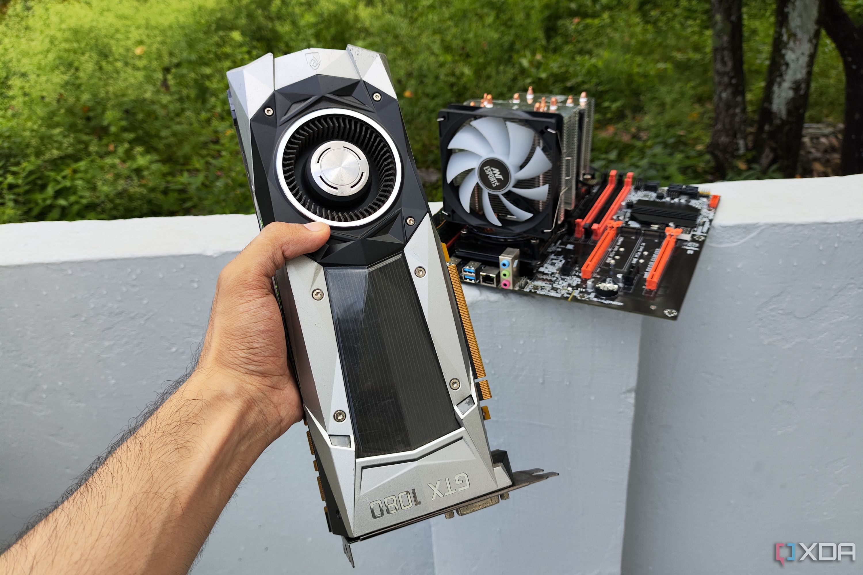 Una persona sostiene una GPU GTX 1080 Founders Edition frente a una PC servidor