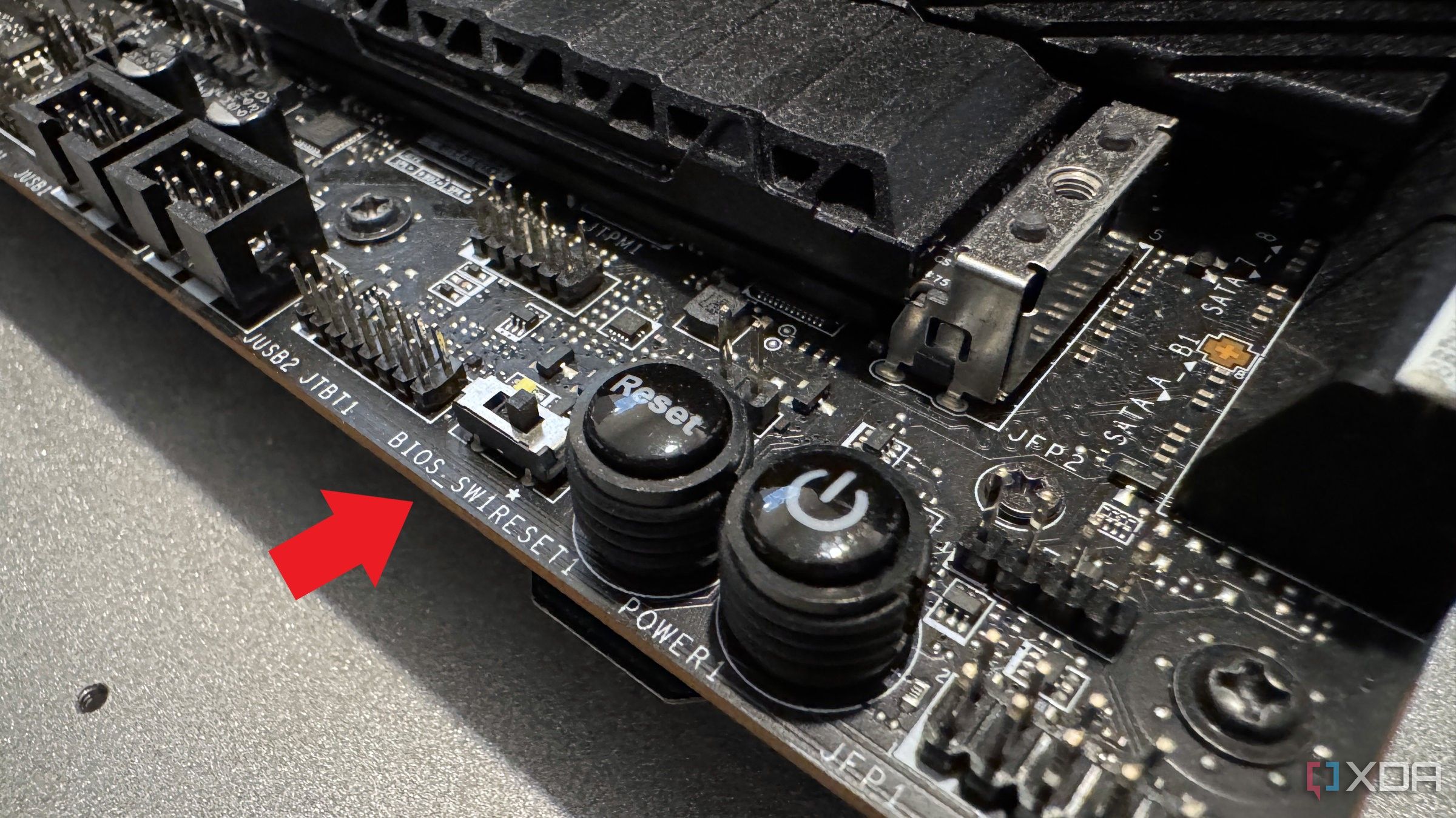 Primer plano de la placa base MSI Z690 Unify-X con una flecha roja que apunta al interruptor de BIOS dual