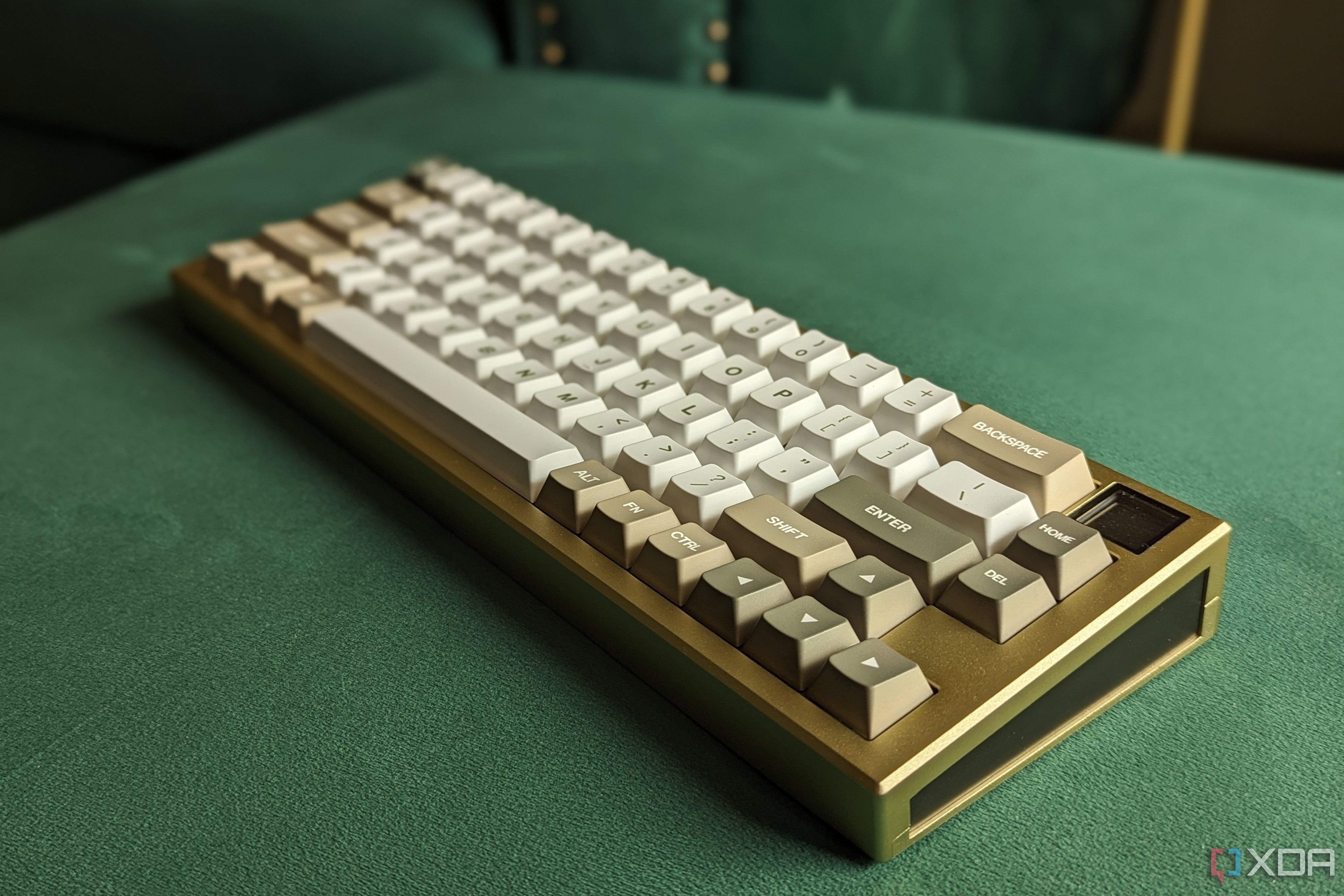 Un teclado mecánico dorado y blanco sobre una superficie verde.