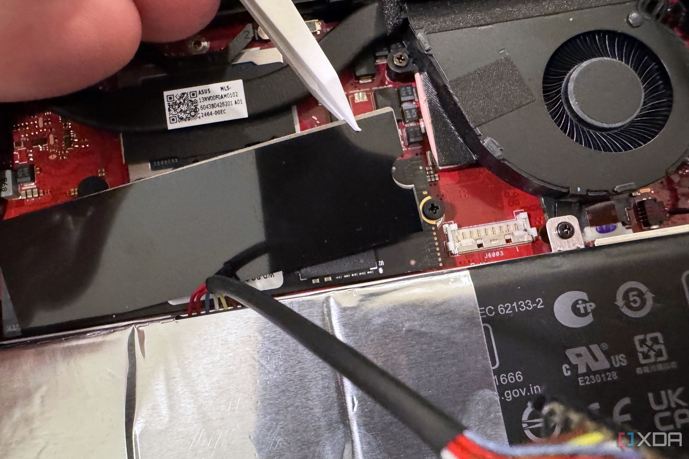 Levantando el escudo térmico sobre el SSD ROG Ally X con un par de pinzas de plástico