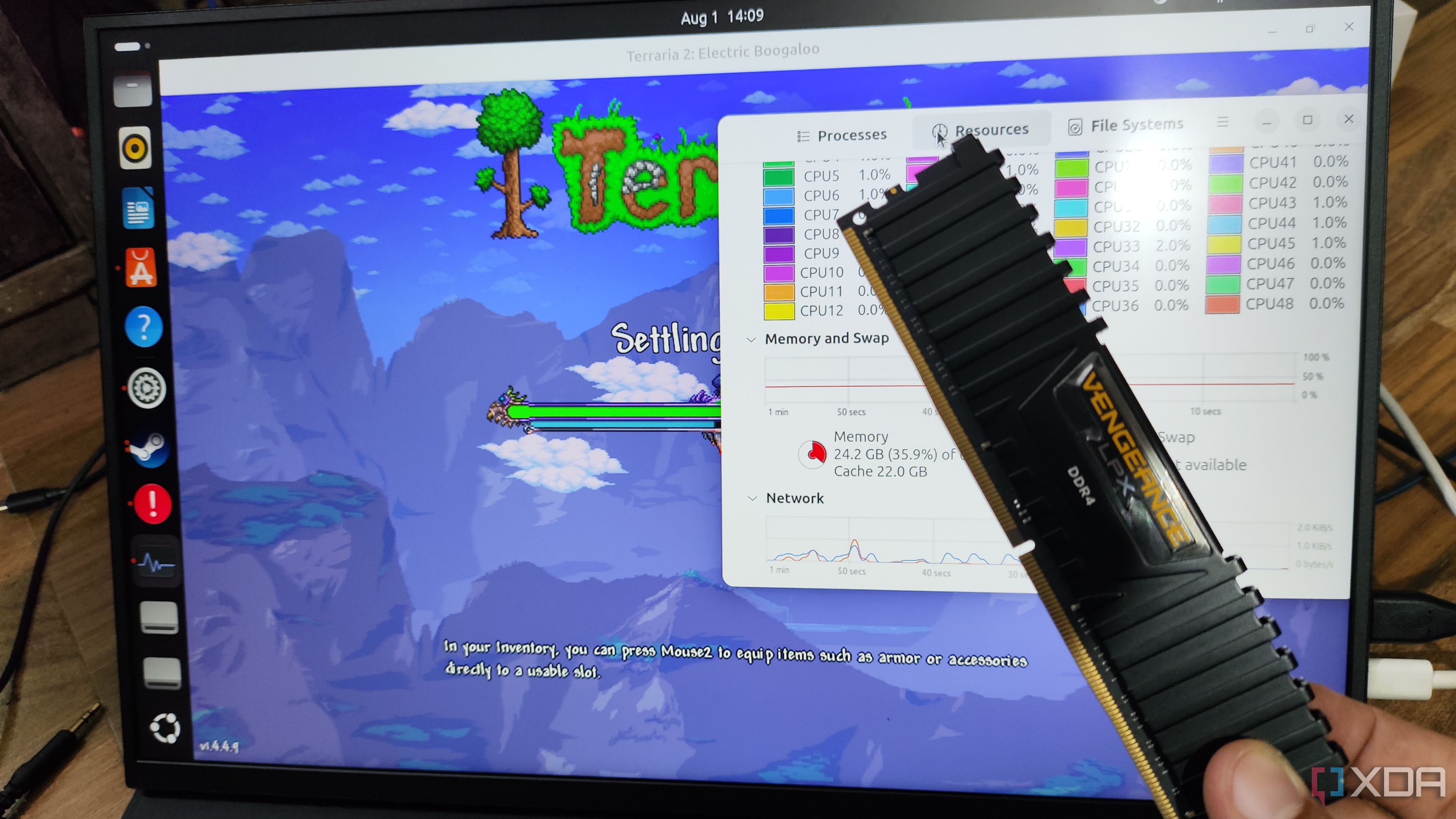 Una persona sostiene una memoria RAM frente a un monitor Uperfect UGame K118 que ejecuta Terraria