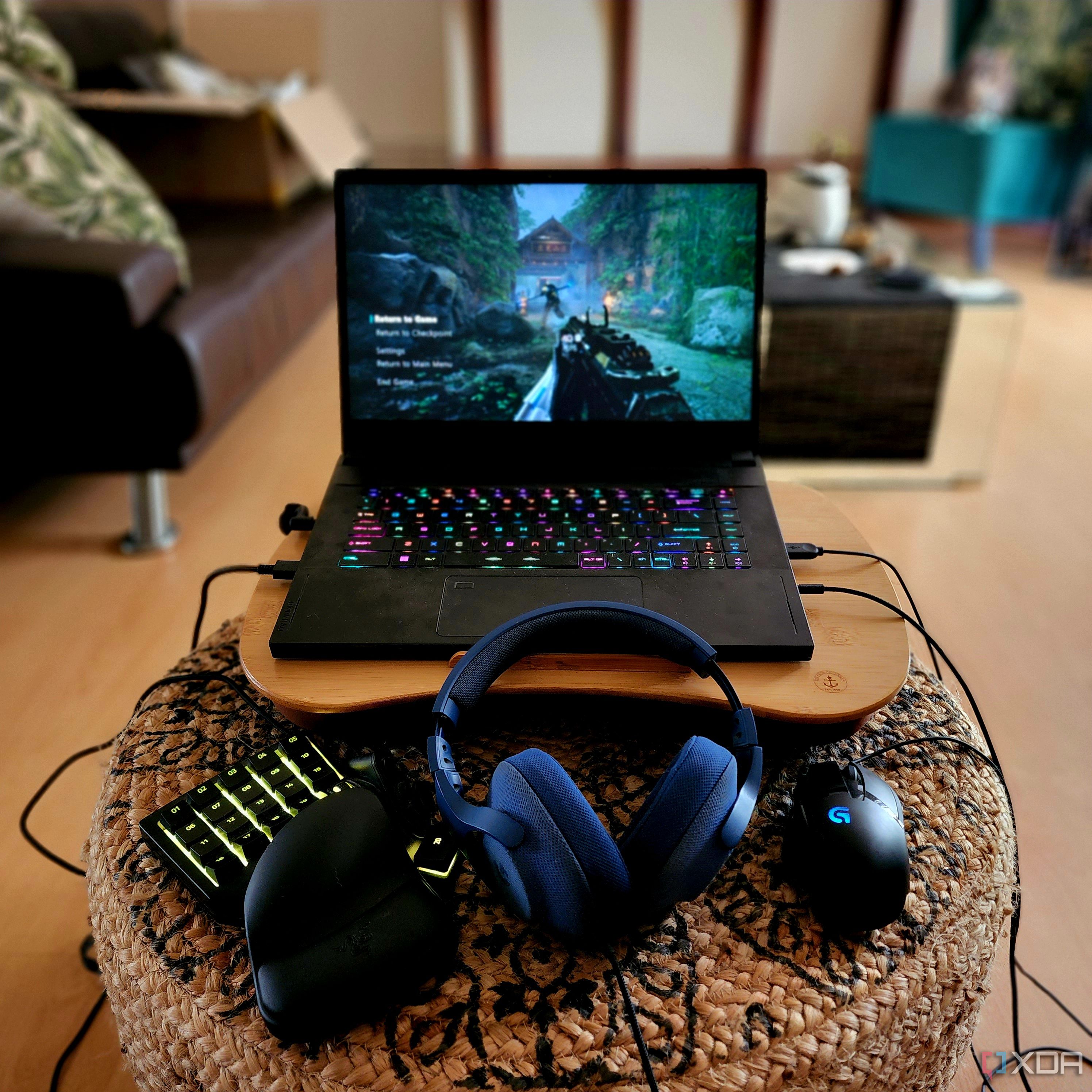 A gaming laptop on a lap desk with peripherals.