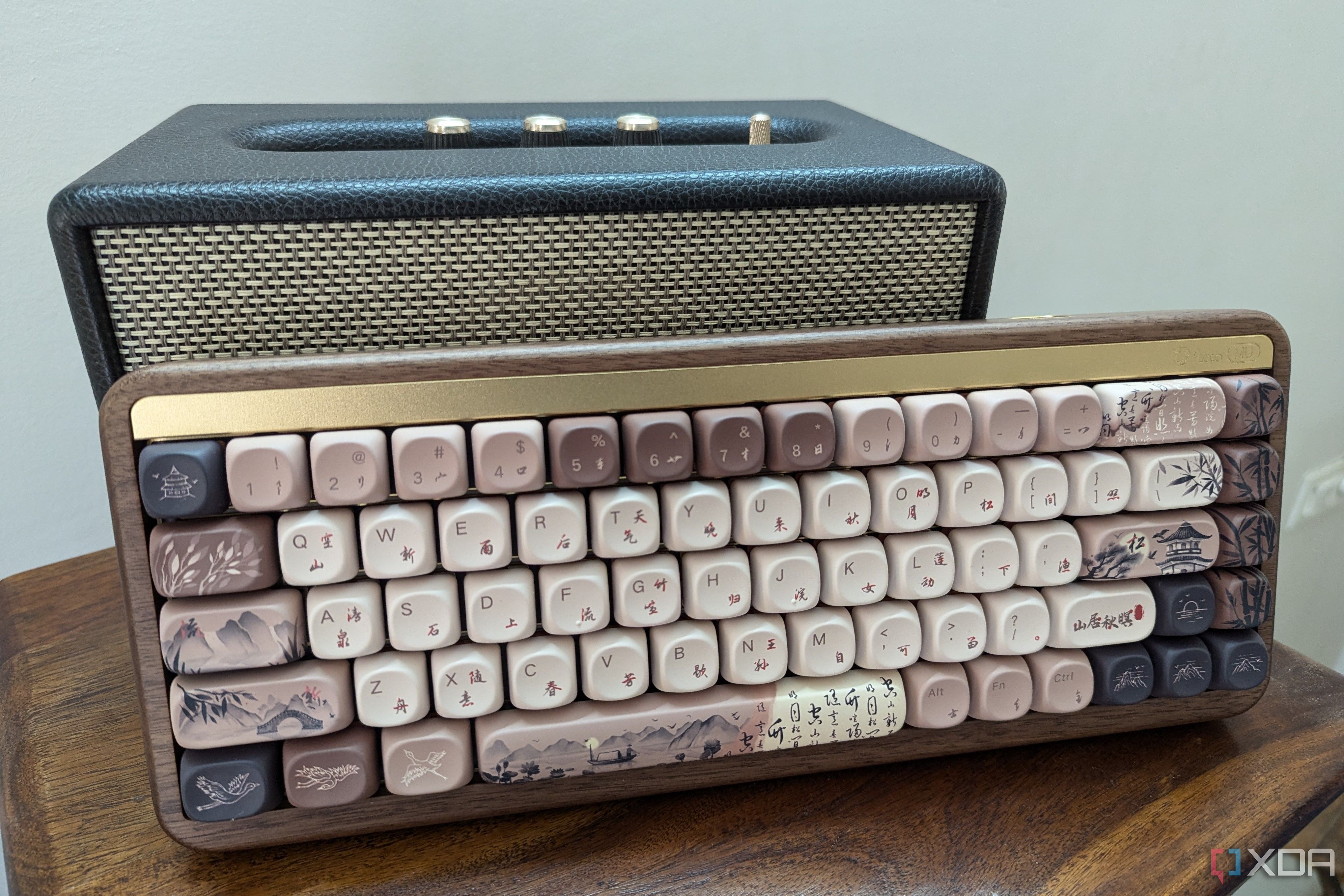 Un teclado mecánico de madera junto a un altavoz sobre una superficie de madera.