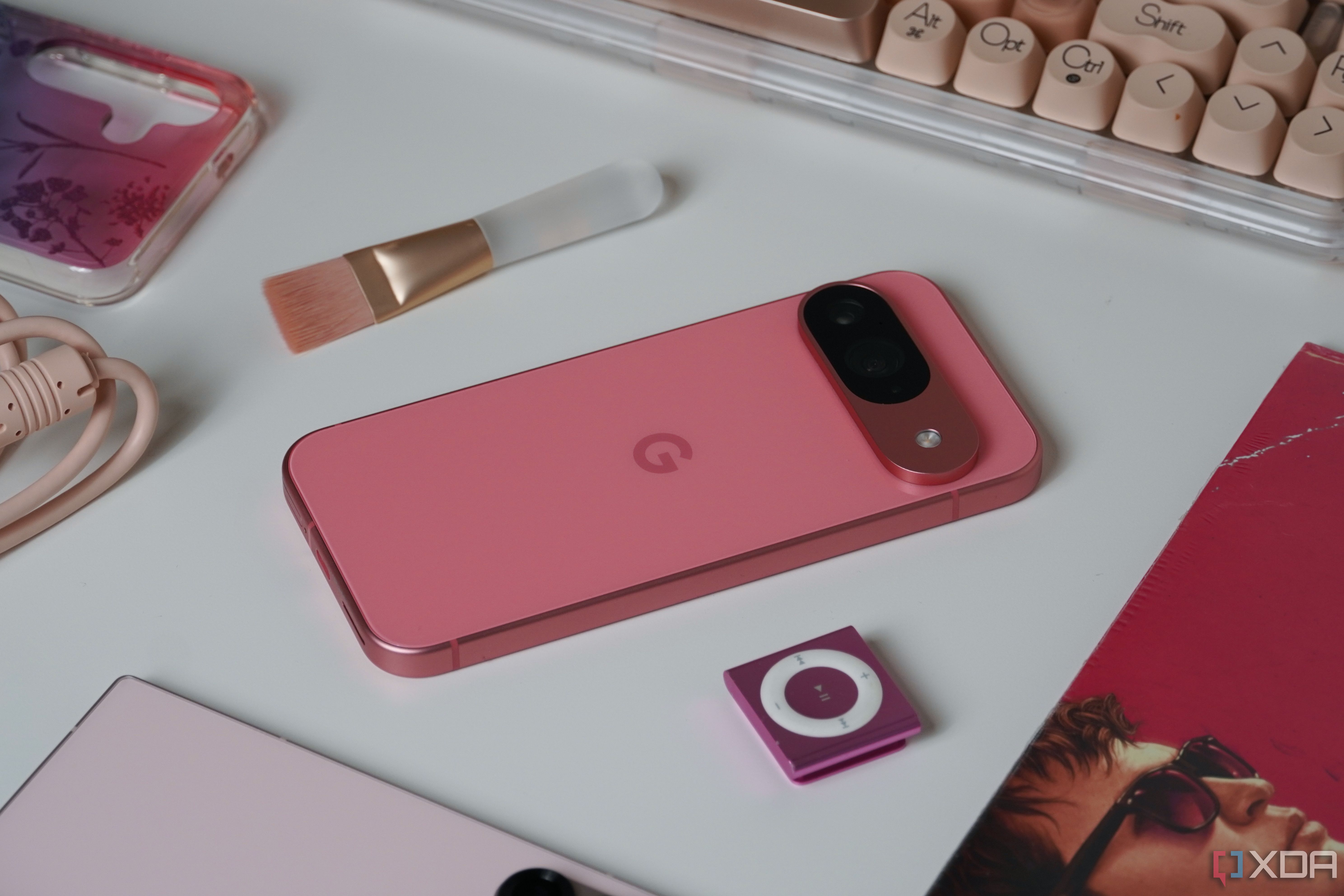 The Google Pixel 9 alongside pink products on a desk.