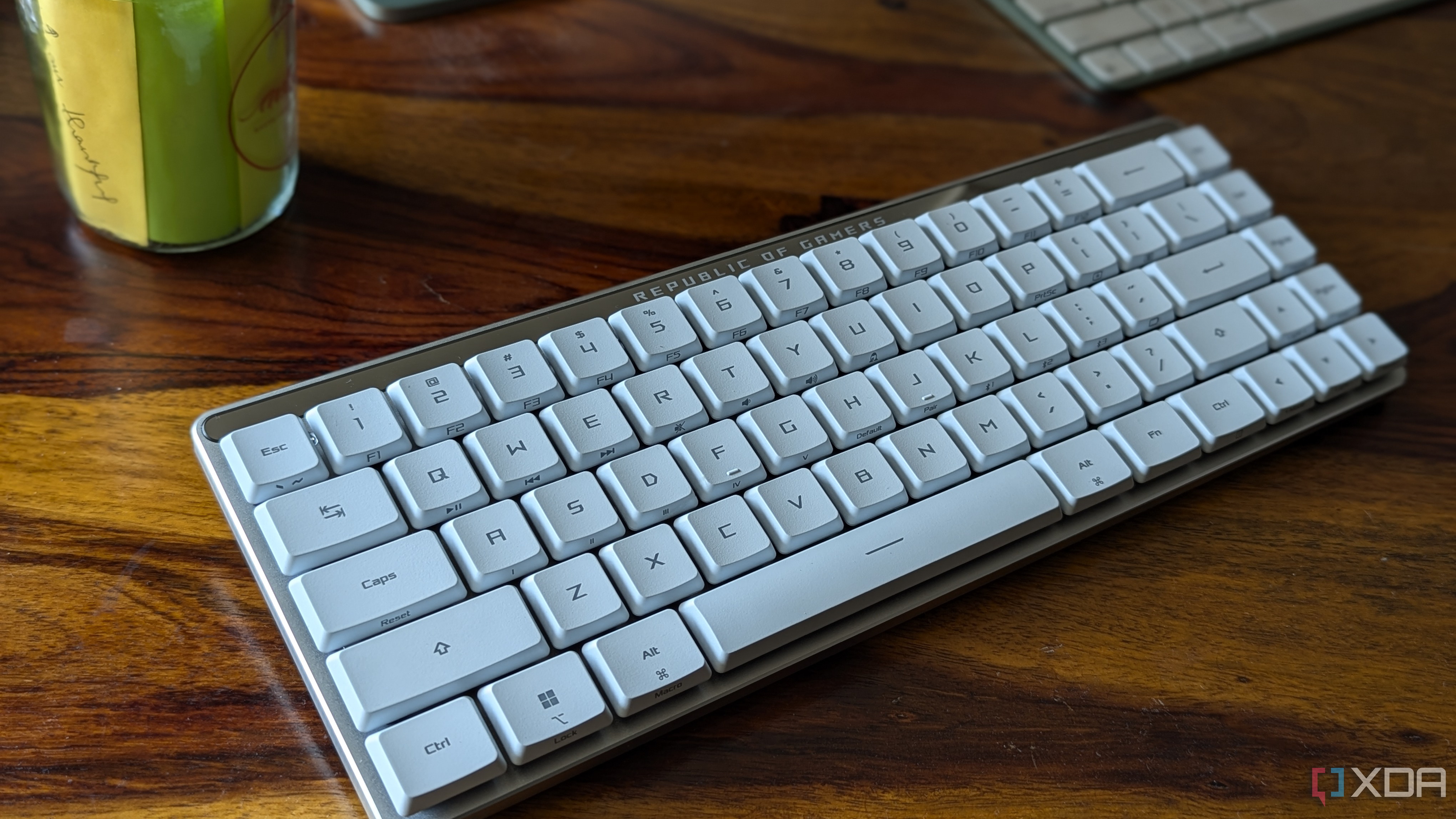 Primer plano de un teclado mecánico blanco de perfil bajo sobre una superficie de madera