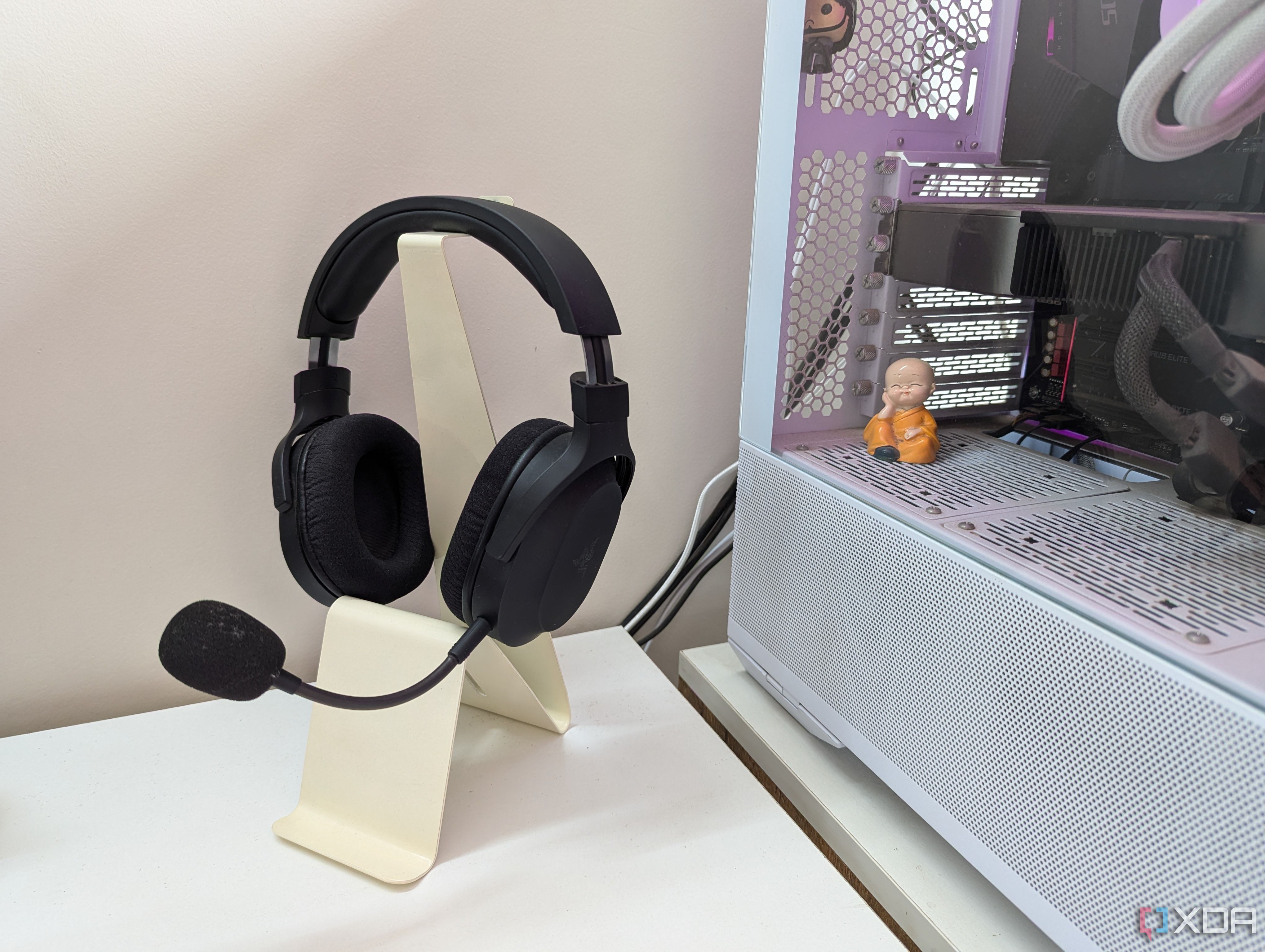 Unos auriculares para juegos en un soporte junto a una PC para juegos en un escritorio blanco