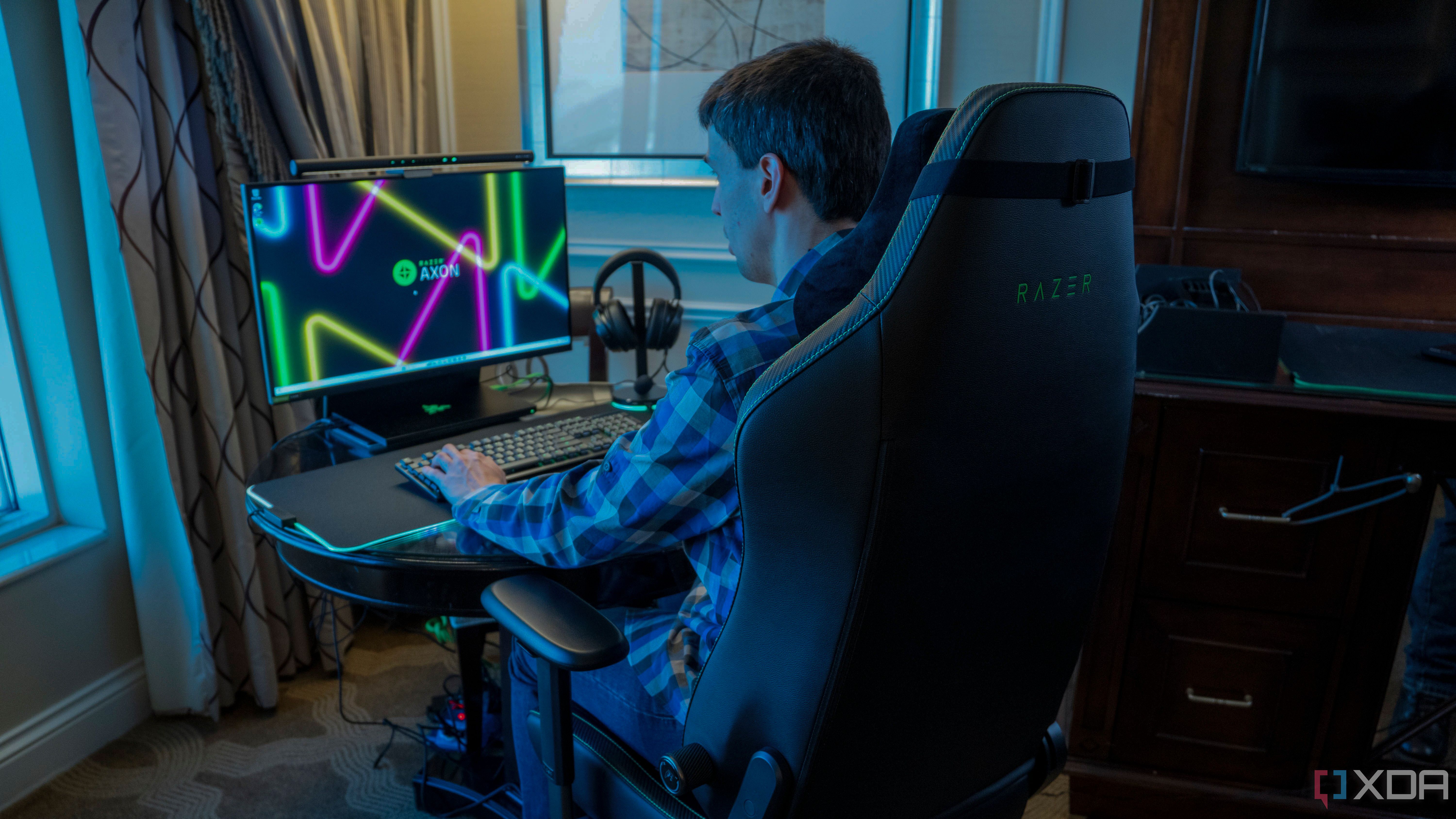 Un hombre sentado frente a un monitor de computadora.