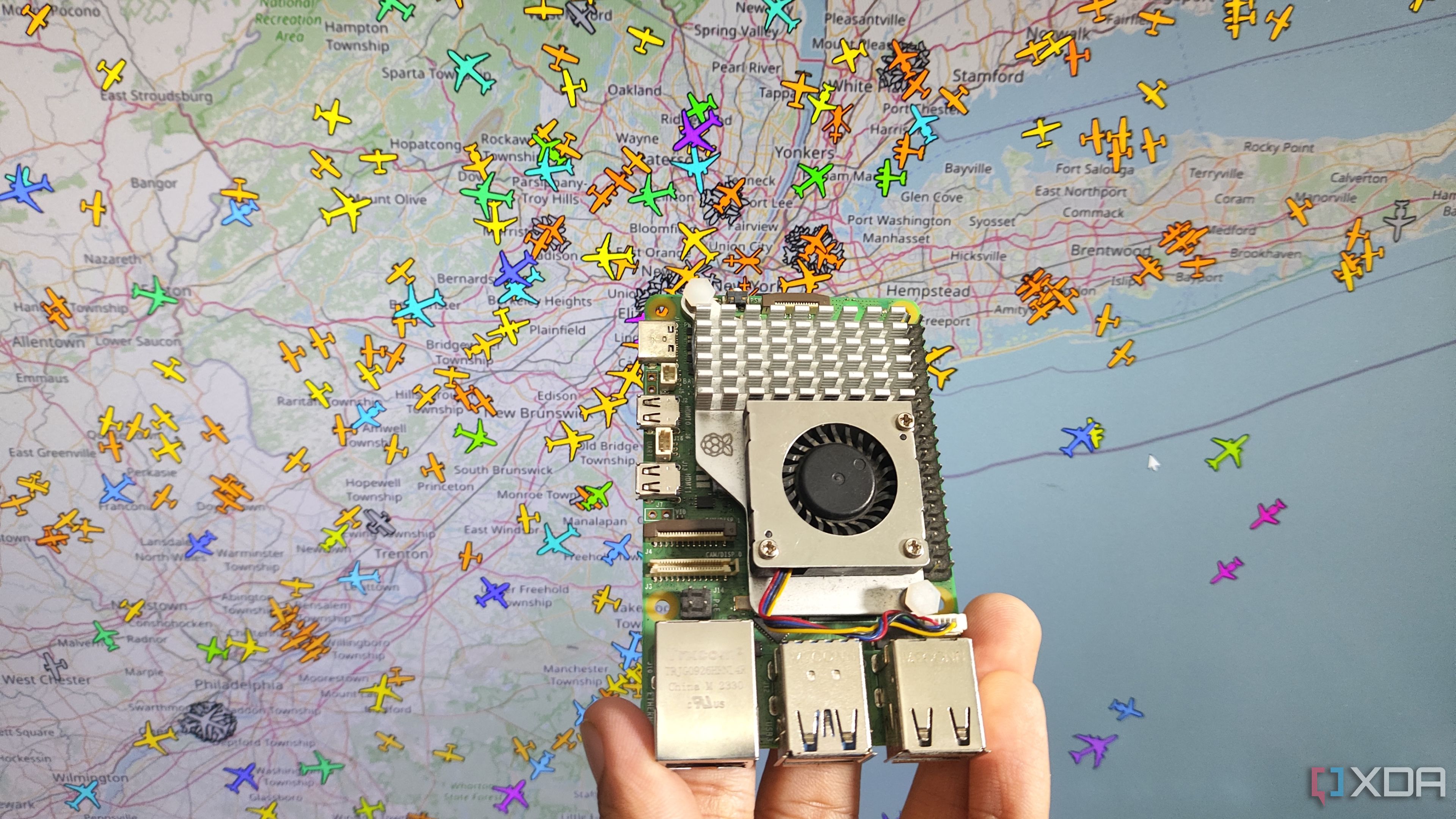 Una persona sostiene una Raspberry Pi 5 frente a un sistema de seguimiento de aviones.