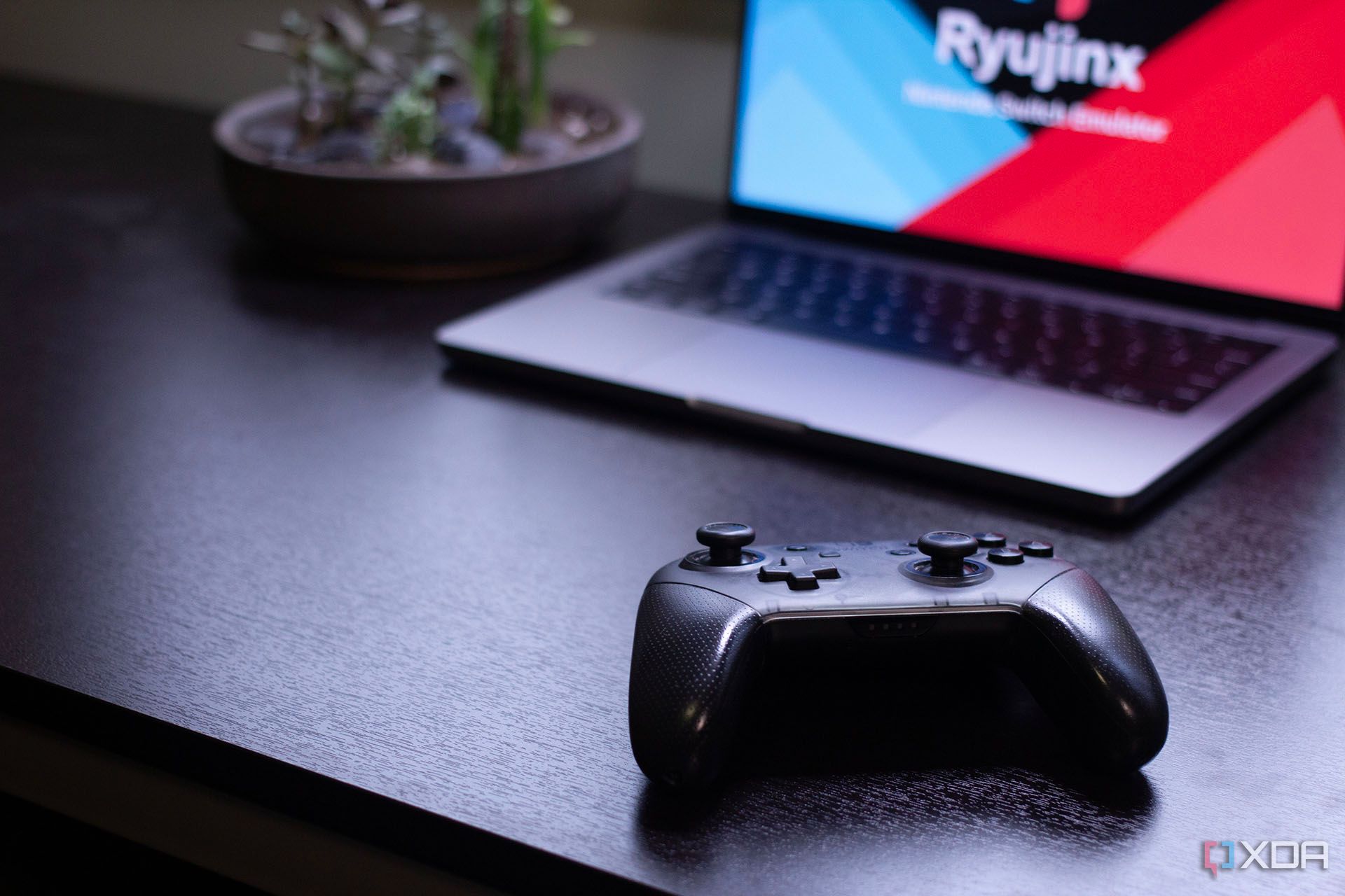 Mando profesional de Nintendo Switch frente a una MacBook con el logotipo de Ryujinx