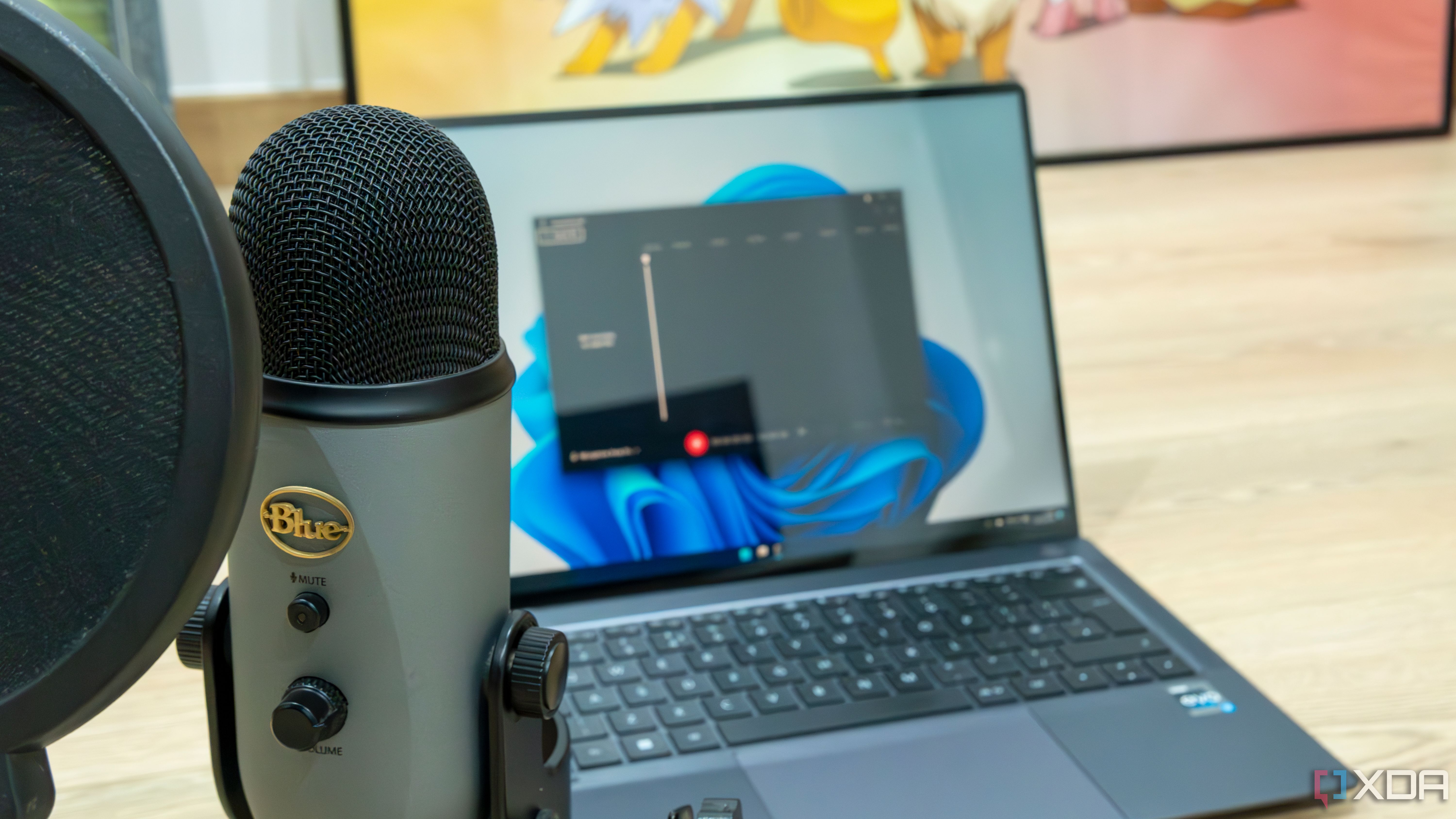 Un micrófono Blue Yeti frente a una computadora portátil con Windows 11 con la grabadora de sonido abierta