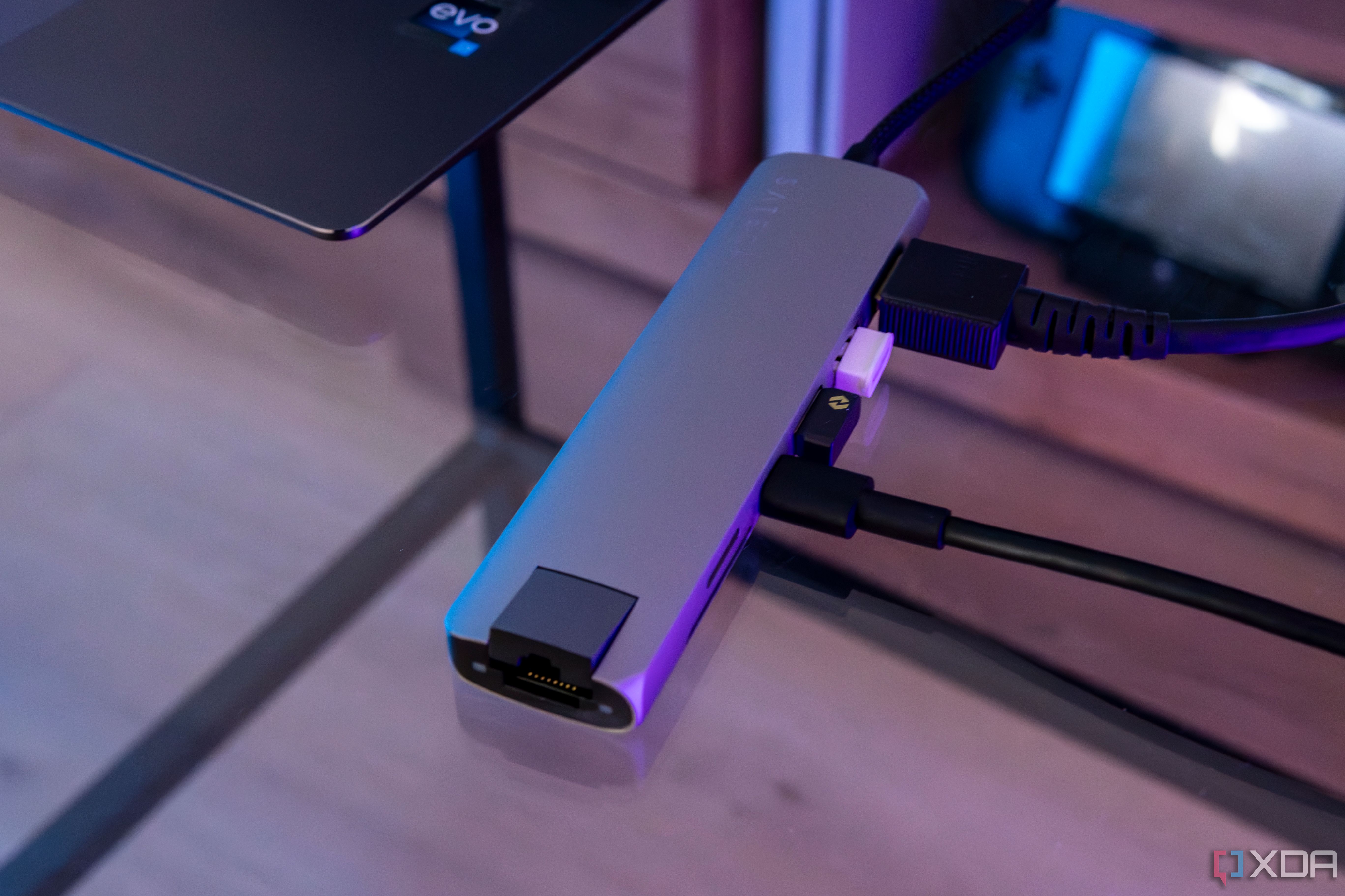 Vista en ángulo del adaptador multipuerto USB-C delgado 7 en 1 de Satechi conectado a una computadora portátil con varios dispositivos conectados