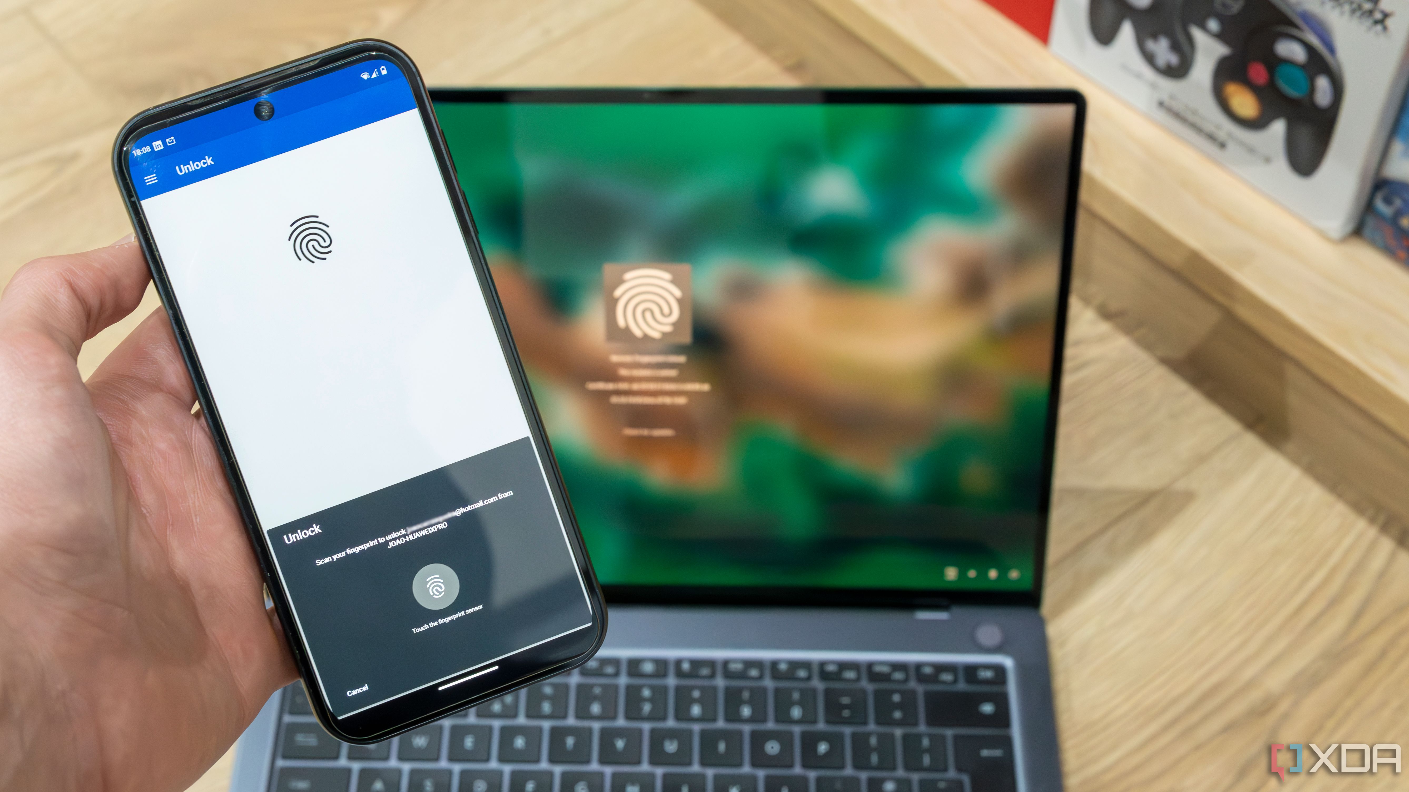Un teléfono Android que ejecuta el desbloqueo remoto por huella digital con una computadora portátil con Windows 11 que muestra la pantalla de bloqueo en segundo plano