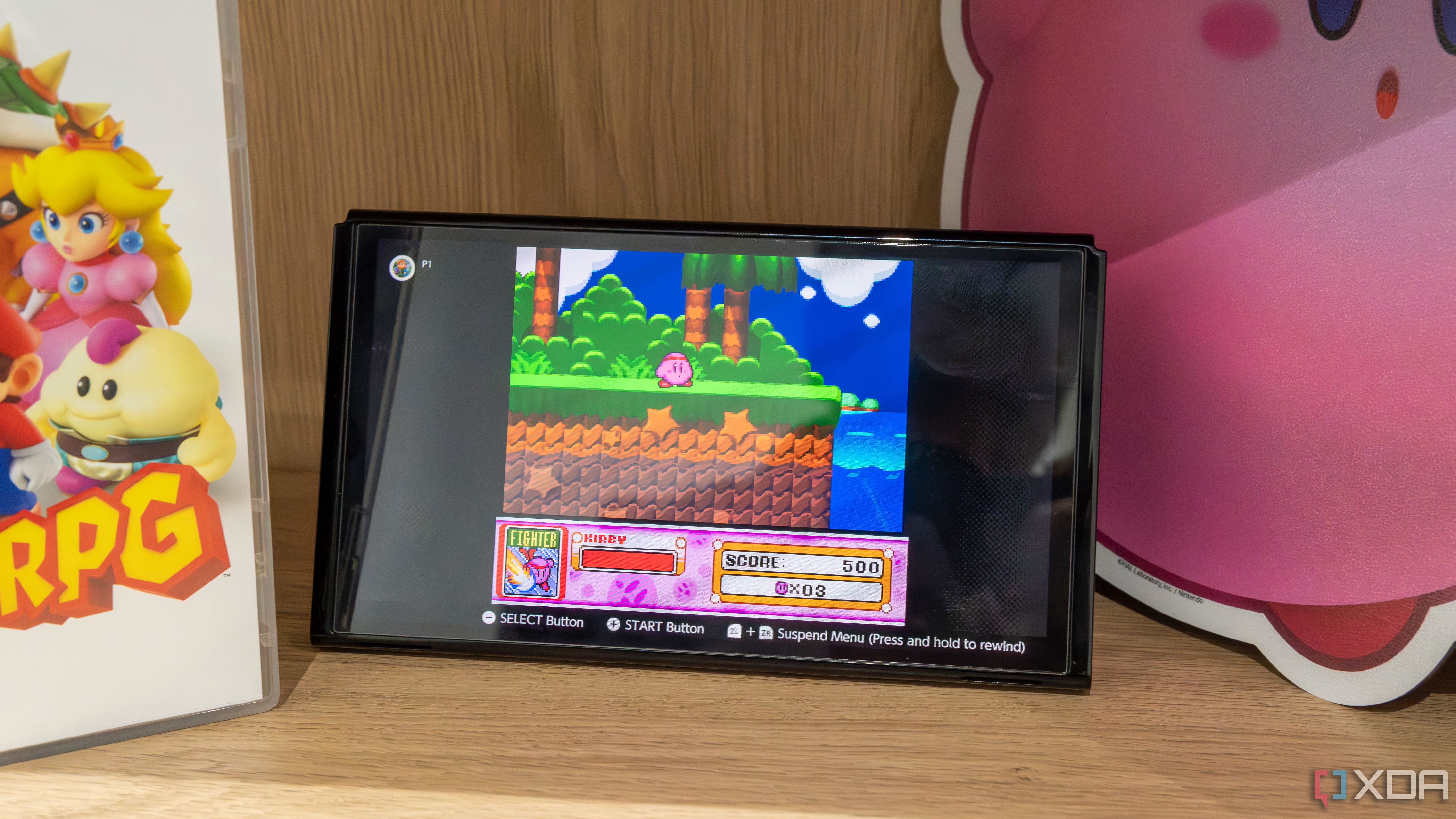 Un modelo OLED de Nintendo Switch con el Joy-Con desmontado mientras se reproduce Kirby Super Star en la aplicación SNES Switch Online