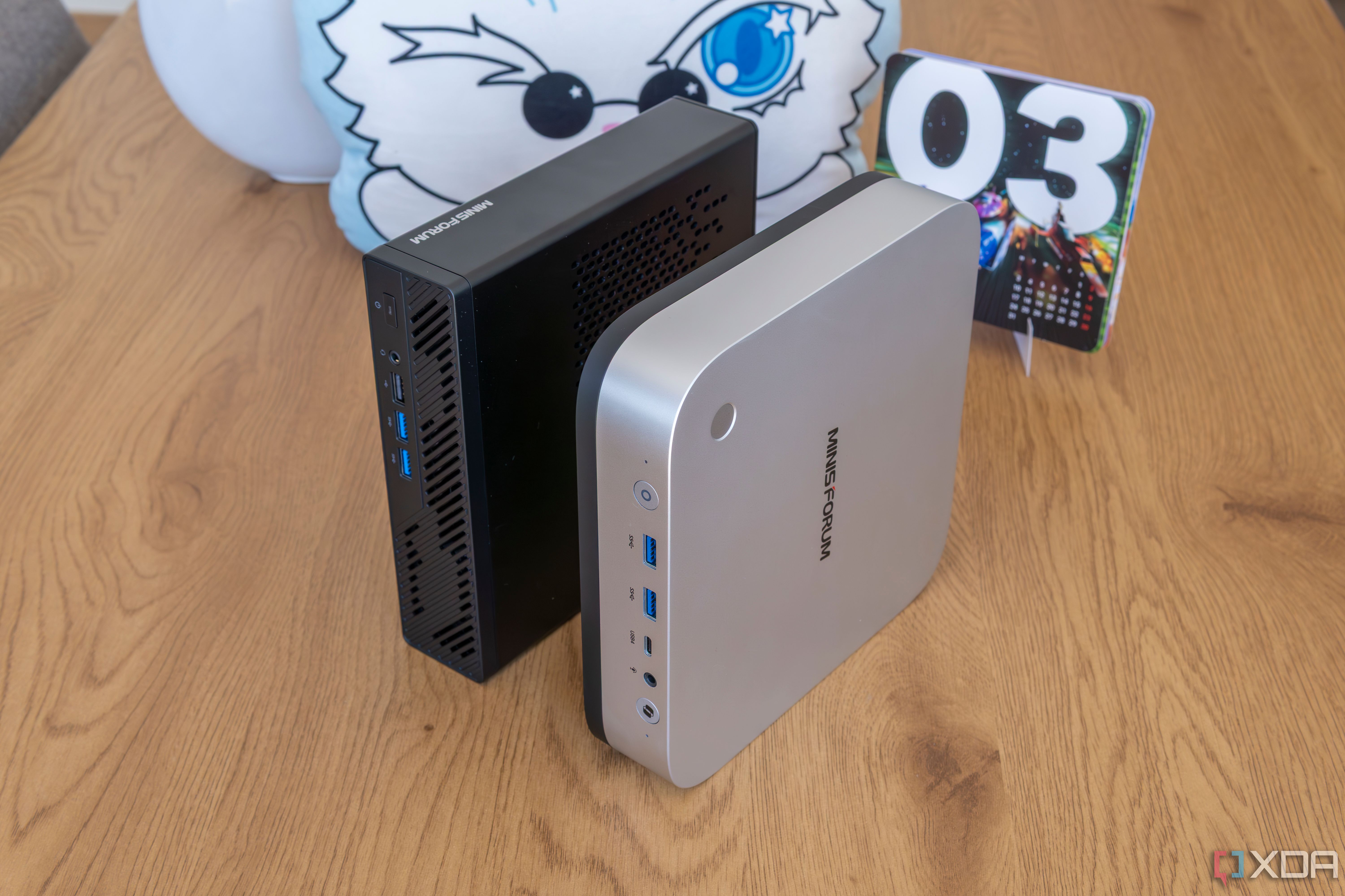 A Minisforum AI X1 Pro standing vertically next to a Minisforum MS-A1 model
