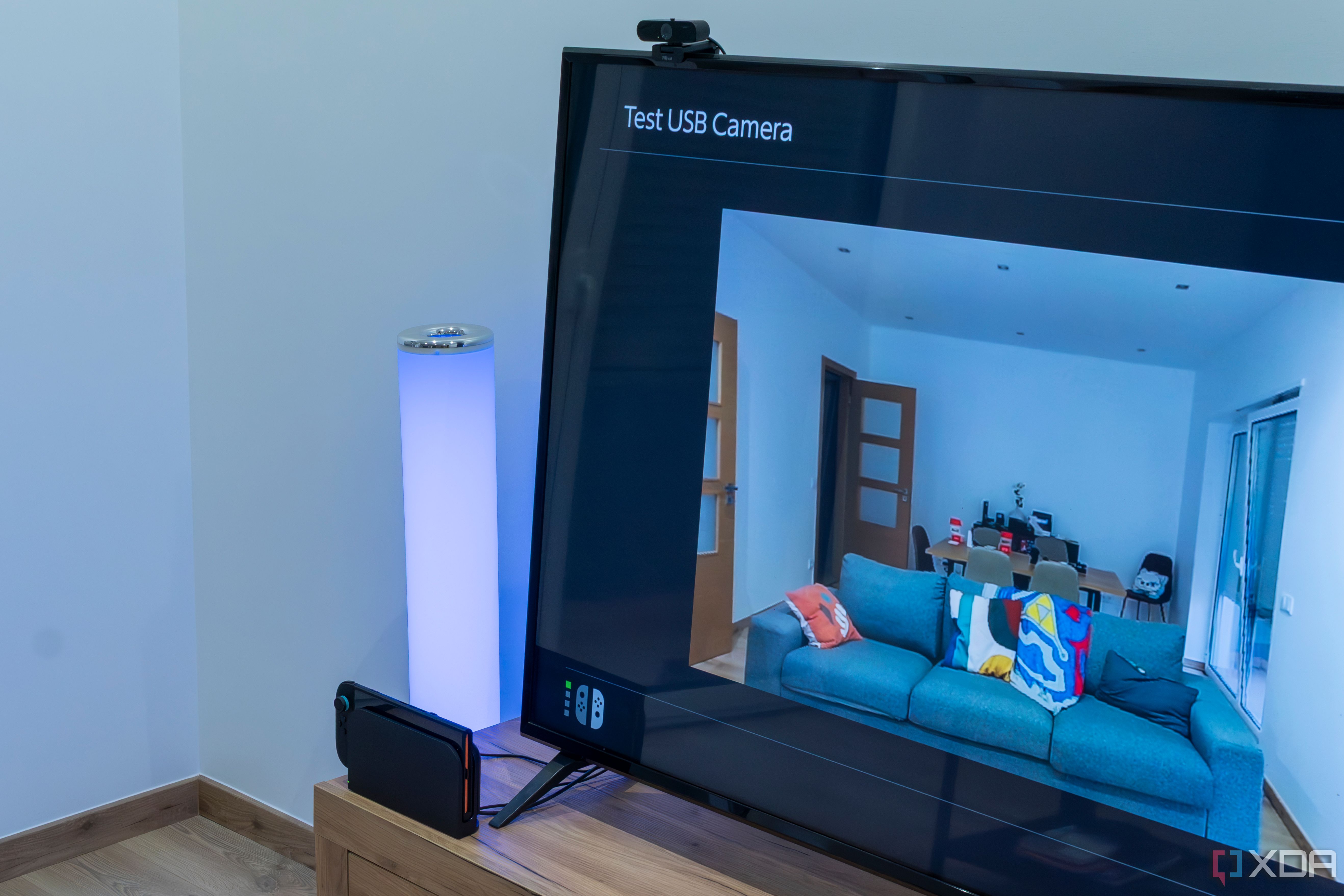 A Nintendo Switch 2 in the dock with a Trust USB webcam connected and showing a preview of the video feed on the TV