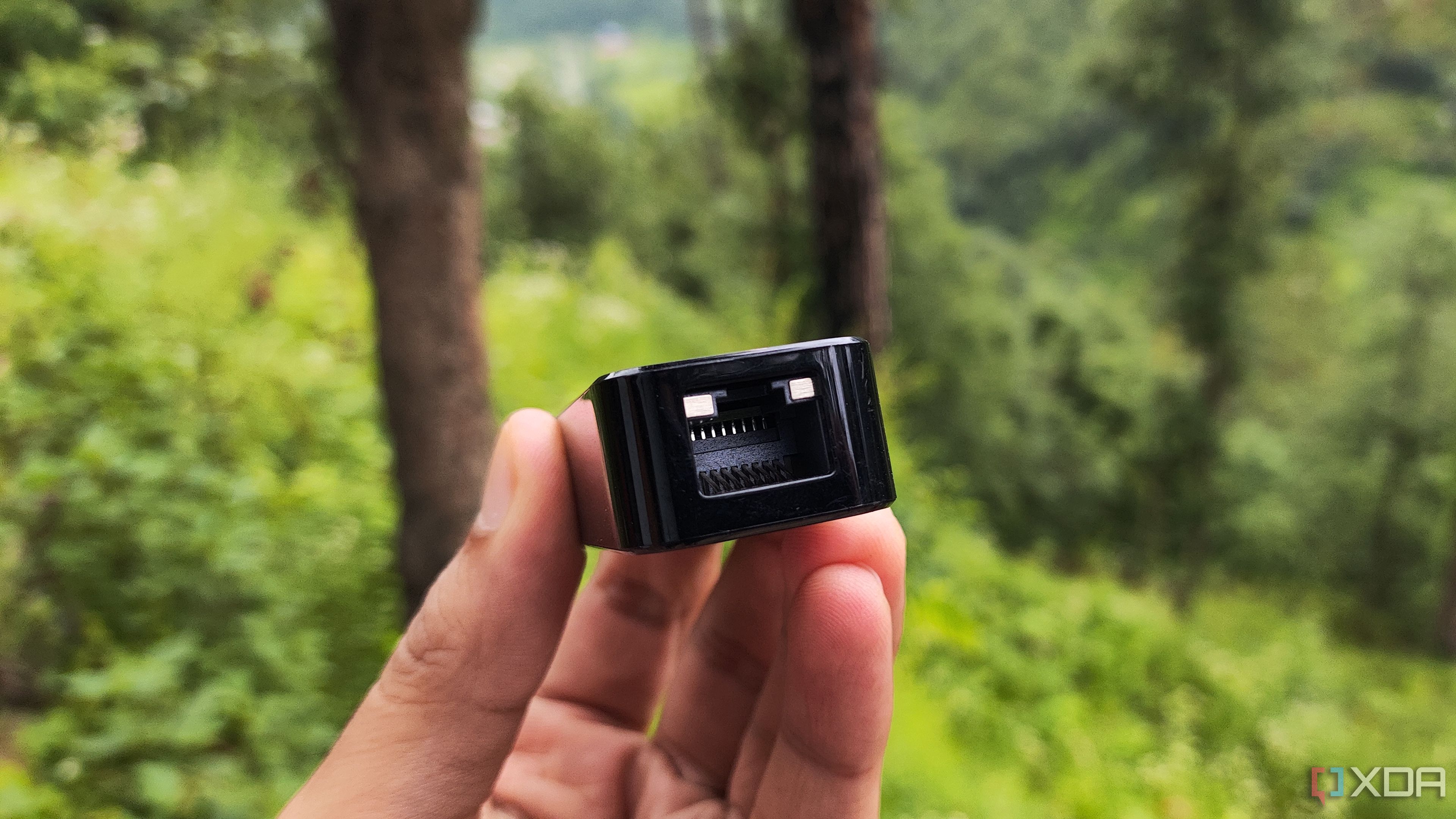 A person holding a USB-to-Ethernet adapter