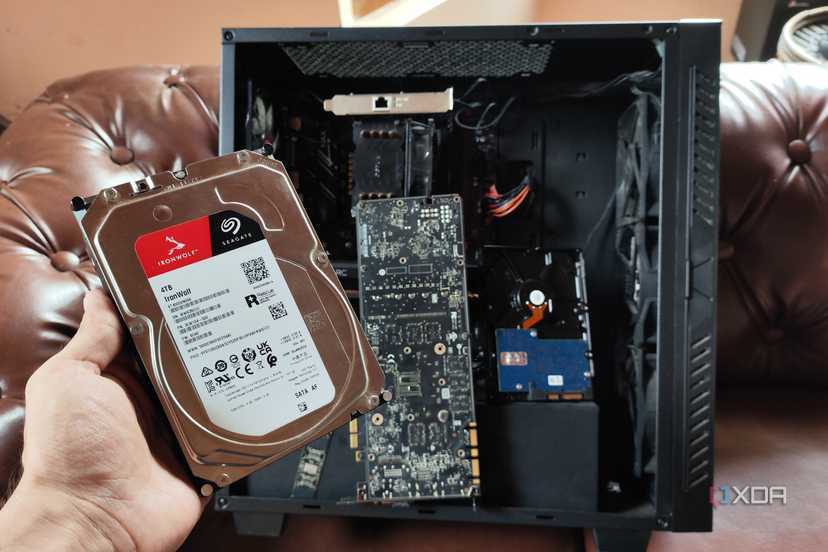 A person holding an HDD in front of a custom-built NAS